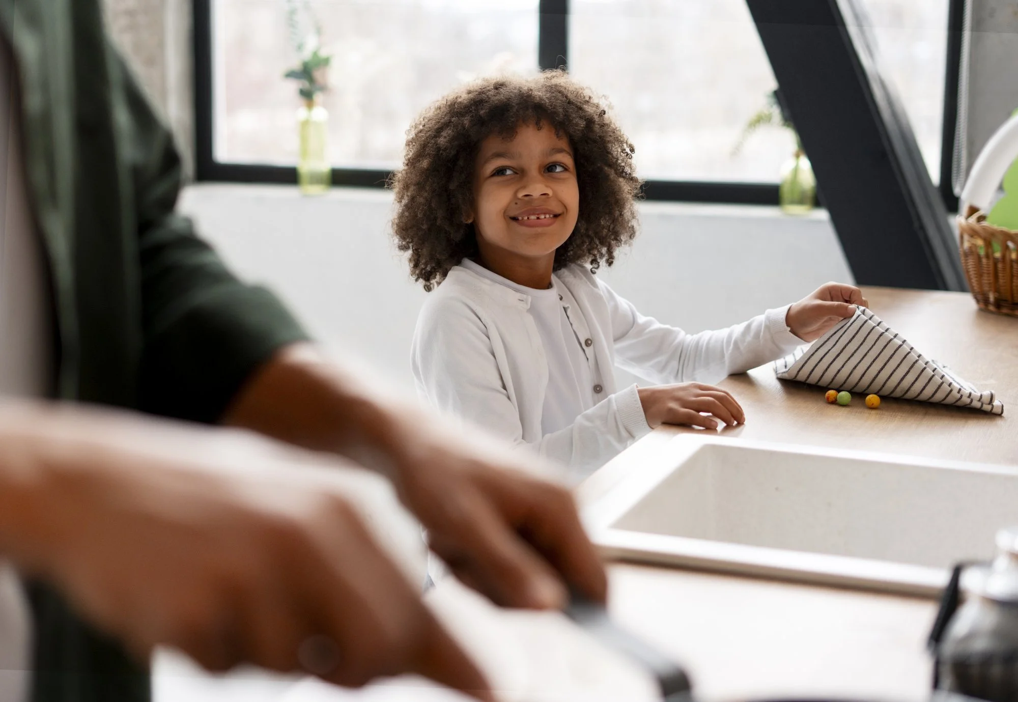 Young student writing at a desk while a tutor guides the lesson nearby.
