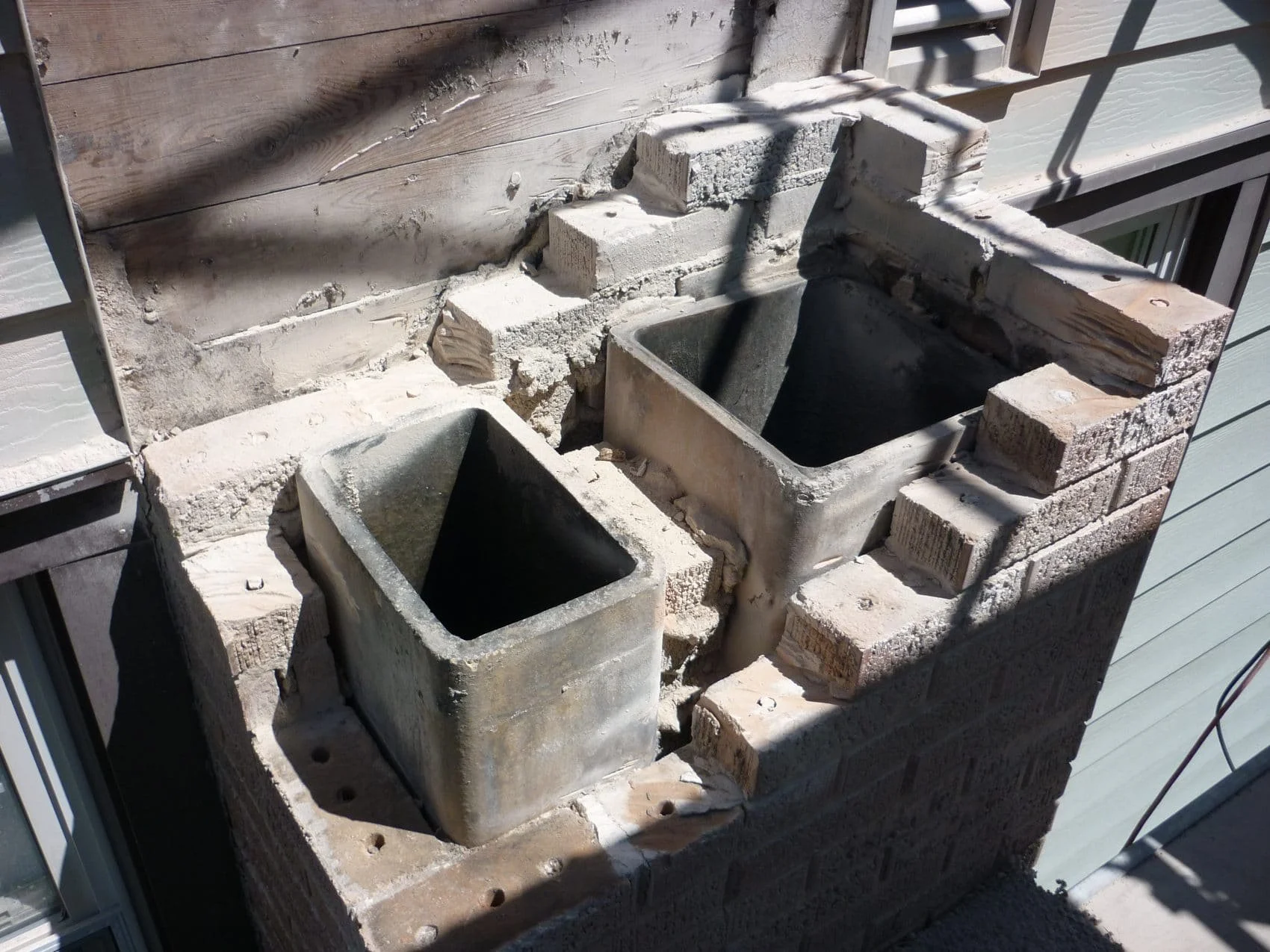 Outdoor construction site with cinder block fire pits and a brick wall under construction.