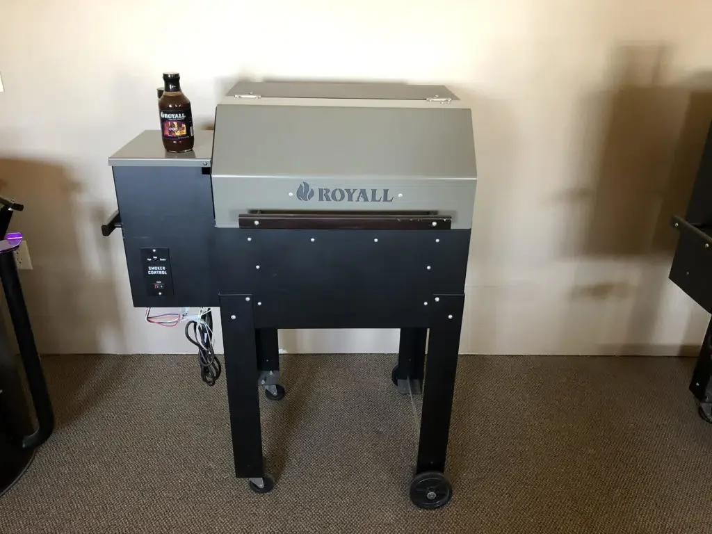 A Royall smoker grill with a bottle of Royall BBQ sauce on top.