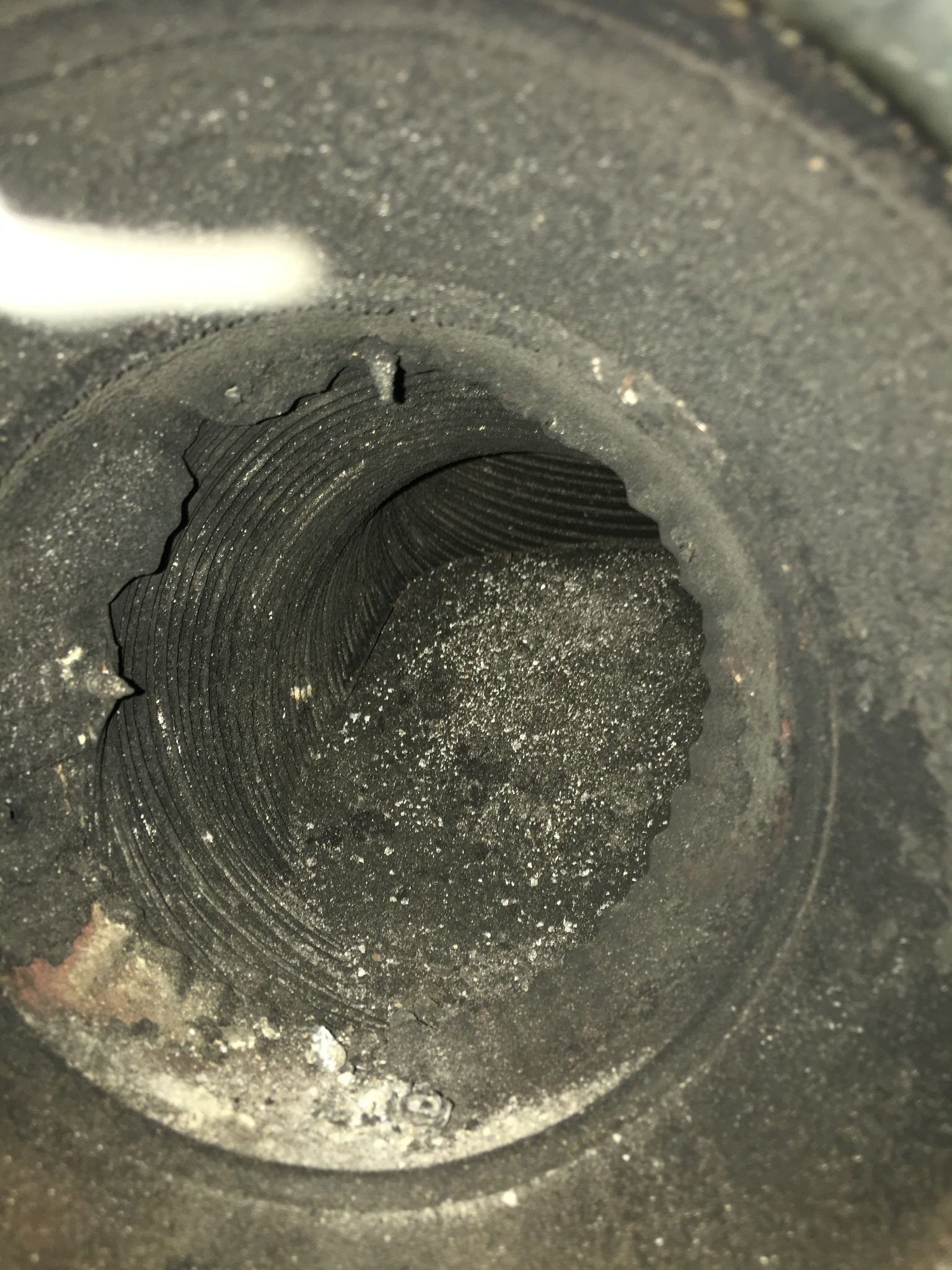 Close-up of the interior of a metal pipe or cylinder showing concentric ridges and some debris or dust.