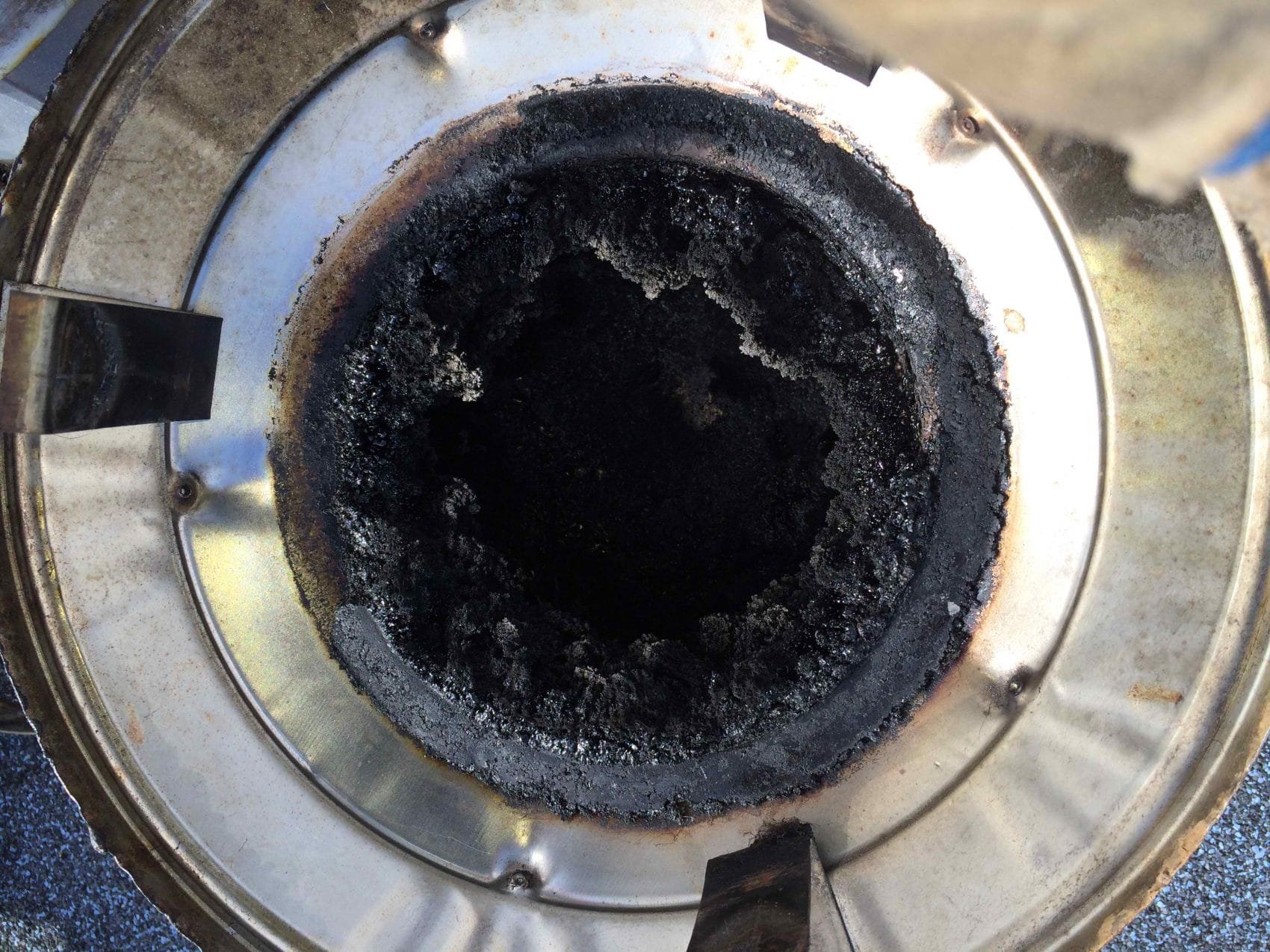 Close-up of an industrial iron or heater with a burnt, charred, and greasy interior surface, likely used for heating or cooking.