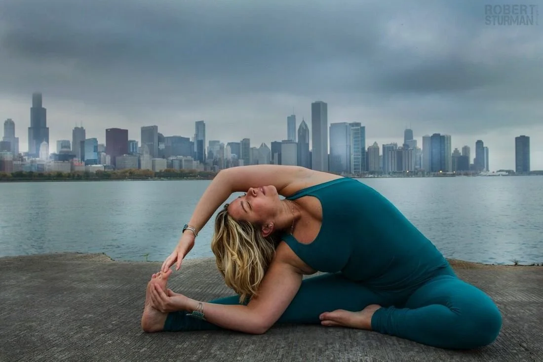 Yoga instructor, Alie McManus in seated yoga pose in a stormy waterfront city