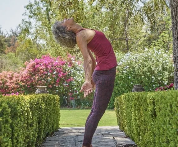 Yoga instructor, Desirée Rumbaugh in standing yoga pose in garden