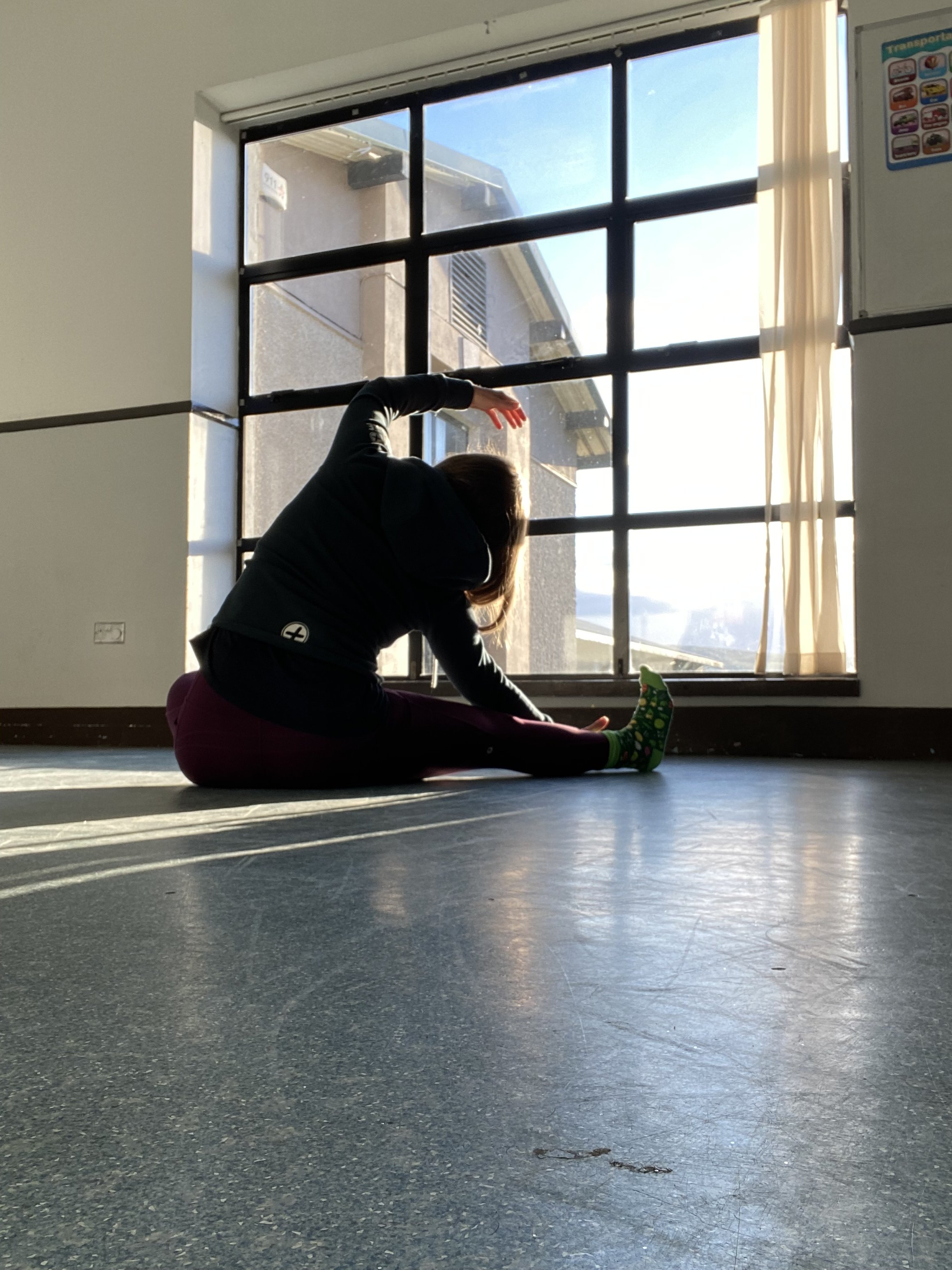 Person practising yoga on a mat in a sunlit room.