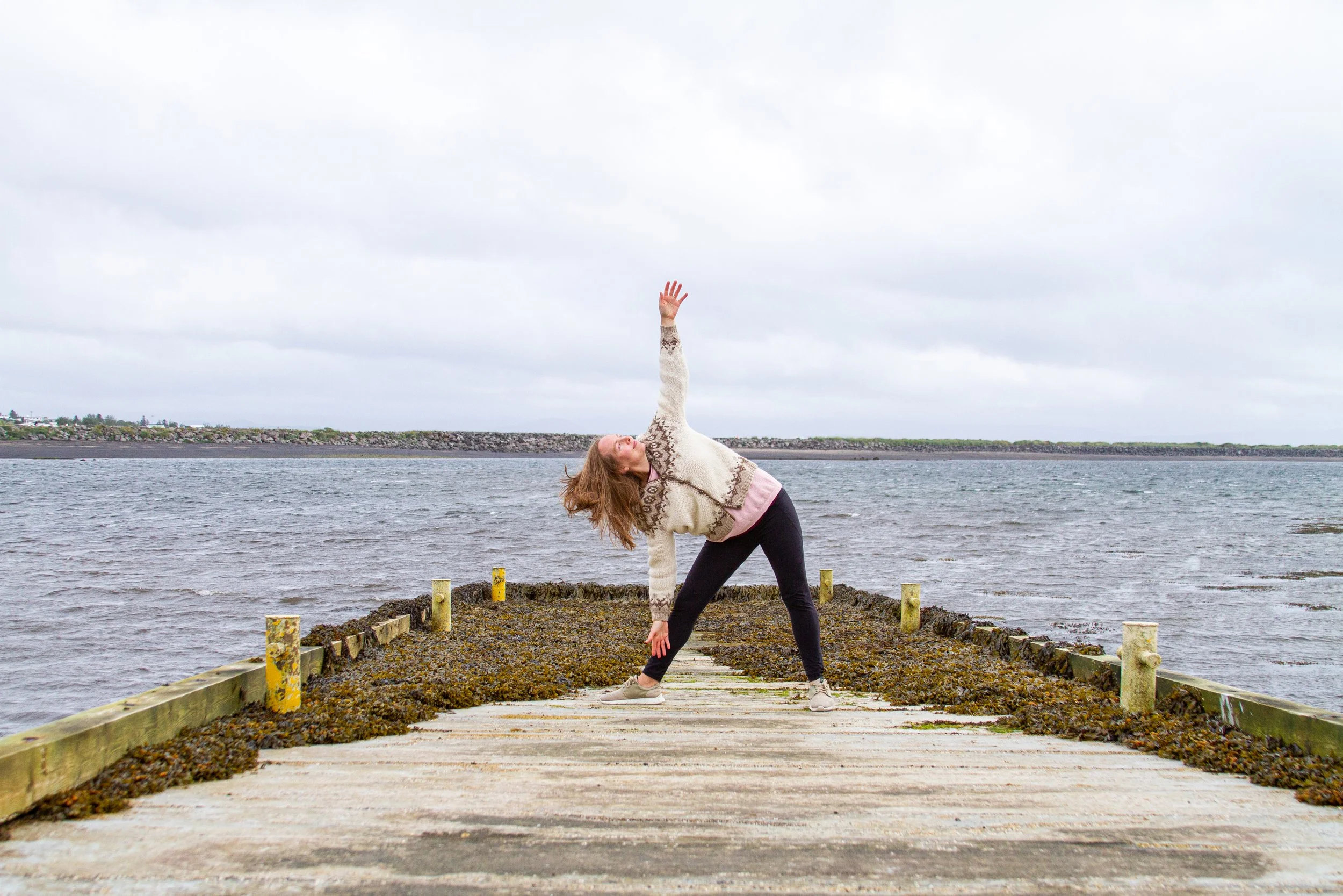 Kristin practising yoga on a wooden dock beside the water.