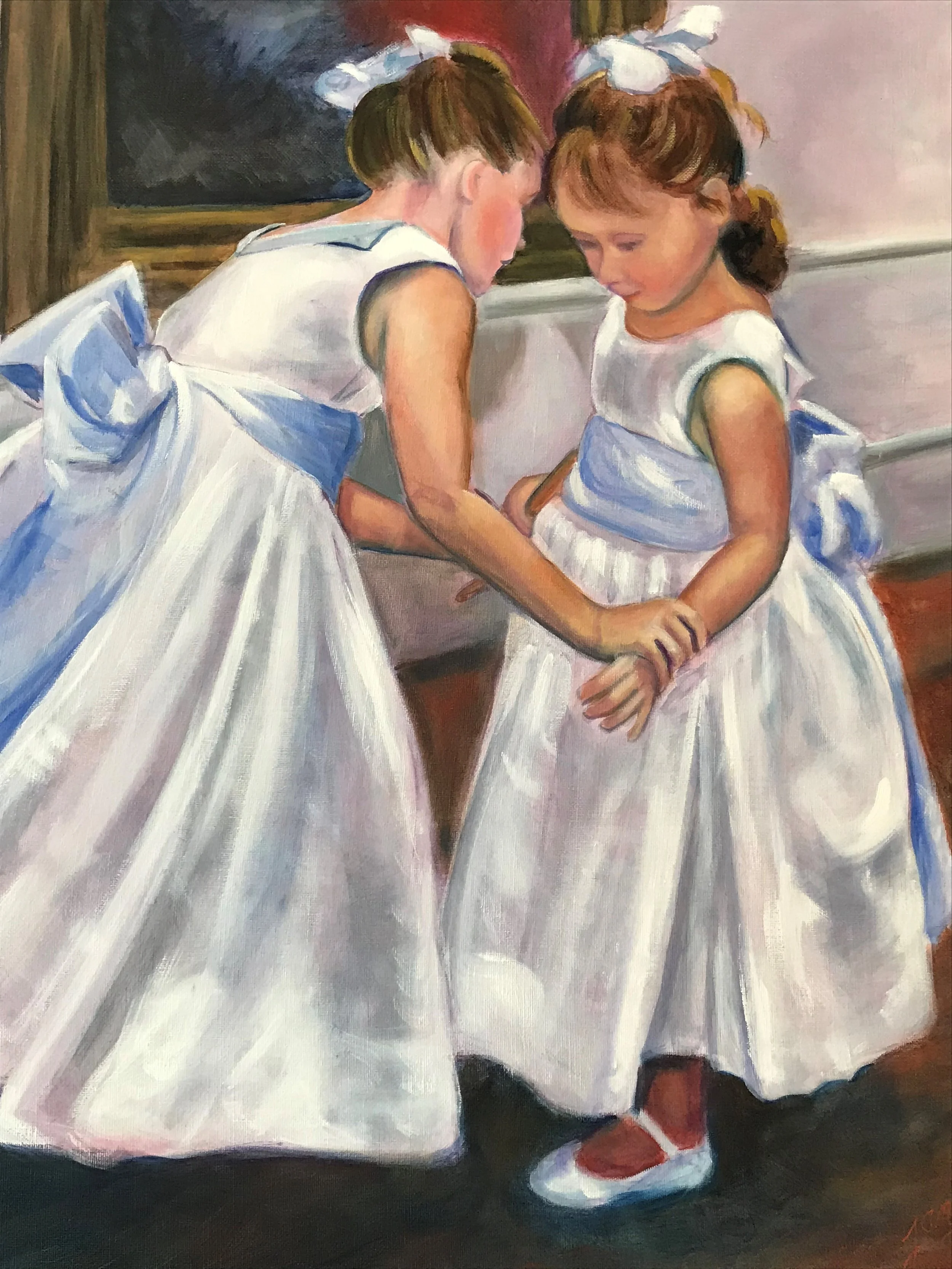 Two young girls in white dresses with bows are holding hands and leaning their heads together, appearing to be whispering to each other in a classroom setting with a chalkboard in the background.