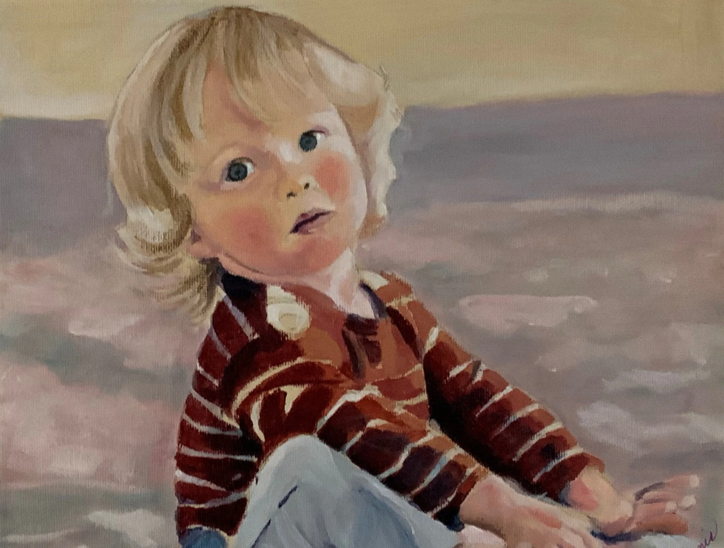 A young boy with blond hair and blue eyes wearing a striped red and brown sweater, playing on the floor.