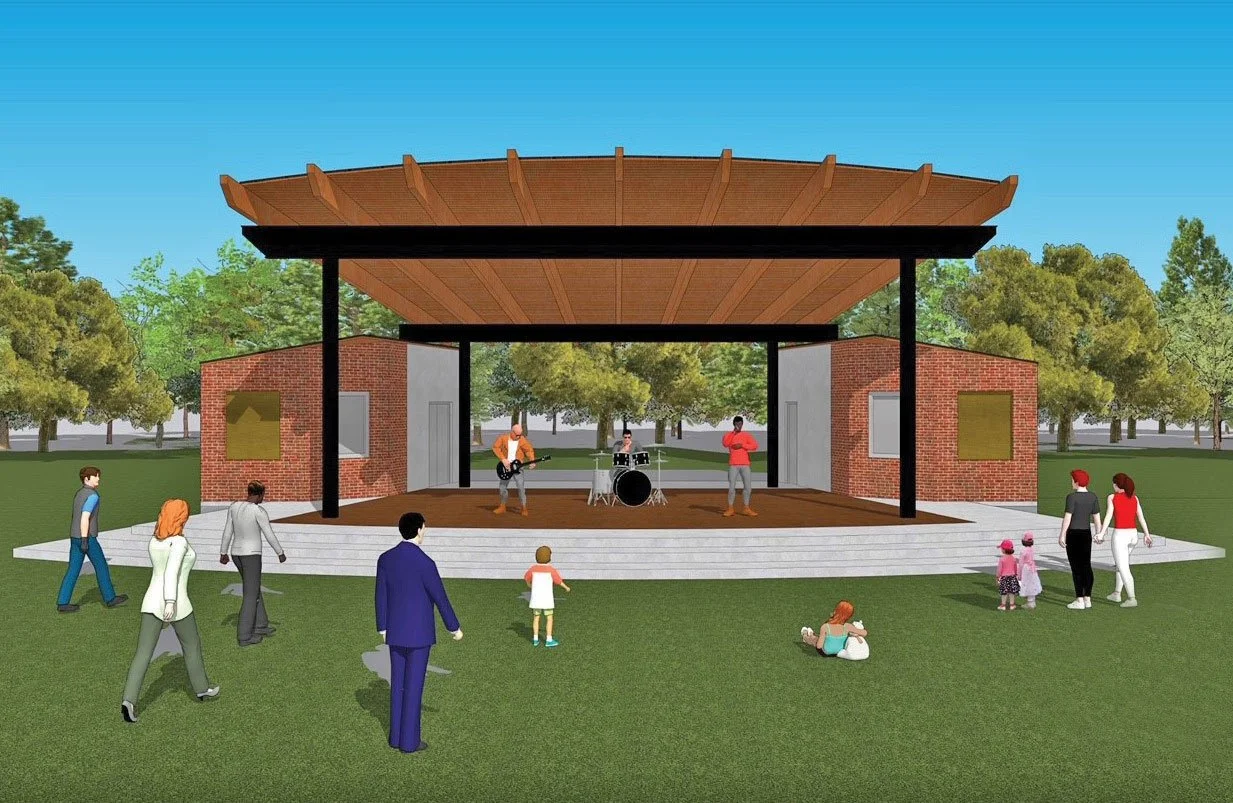 An outdoor stage with a wooden roof and brick sides, where a live band is performing. Audience members, including children and adults, are watching and walking around on a grassy area with trees in the background on a clear day.