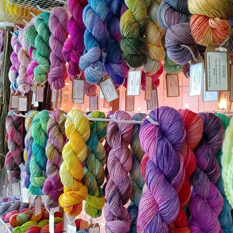 Colorful skeins of yarn hung for display on a store rack.