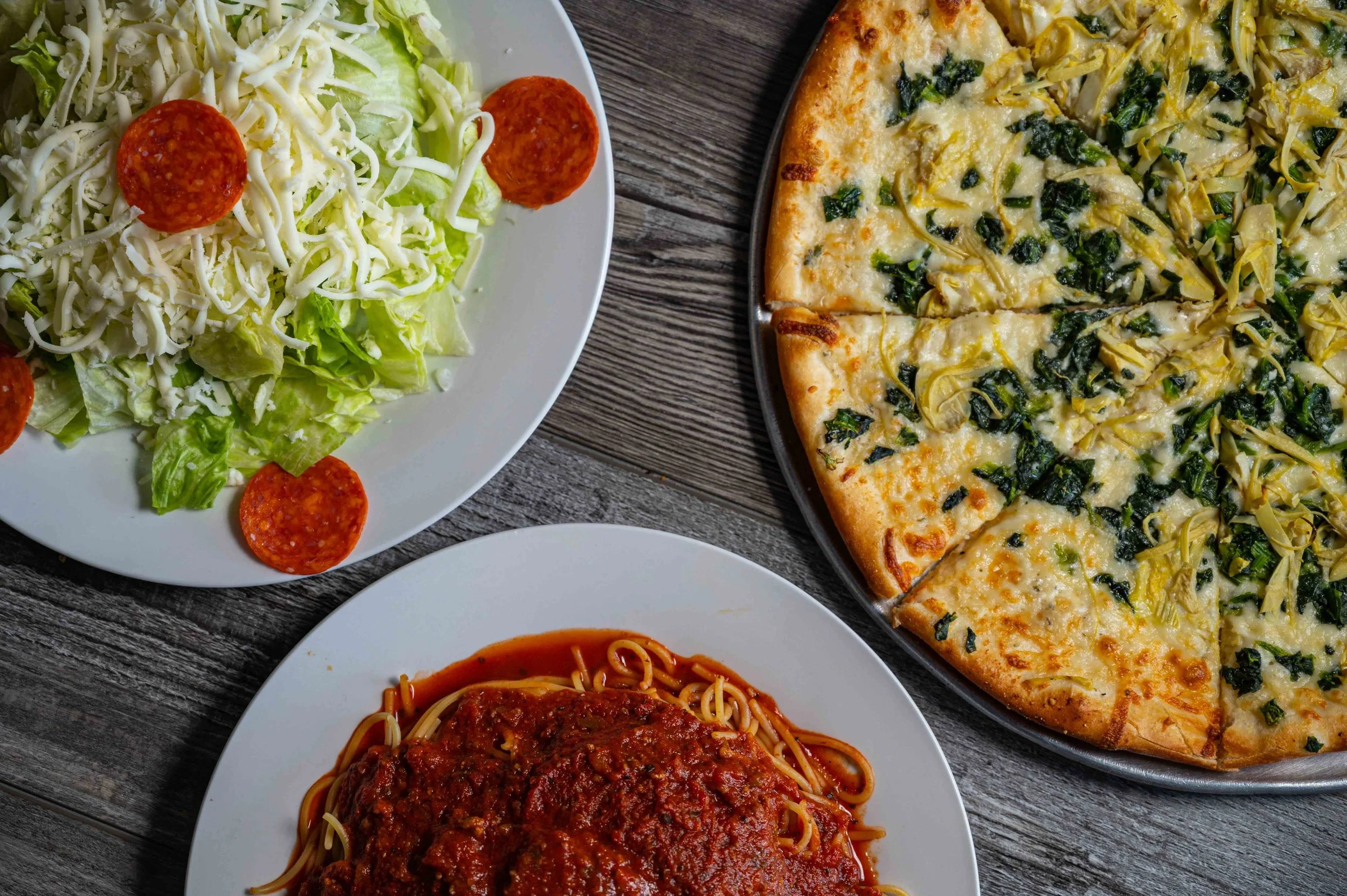 Pizza, spagnetti with sauce and house salad with lettuce, mozzarella and pepperoni.