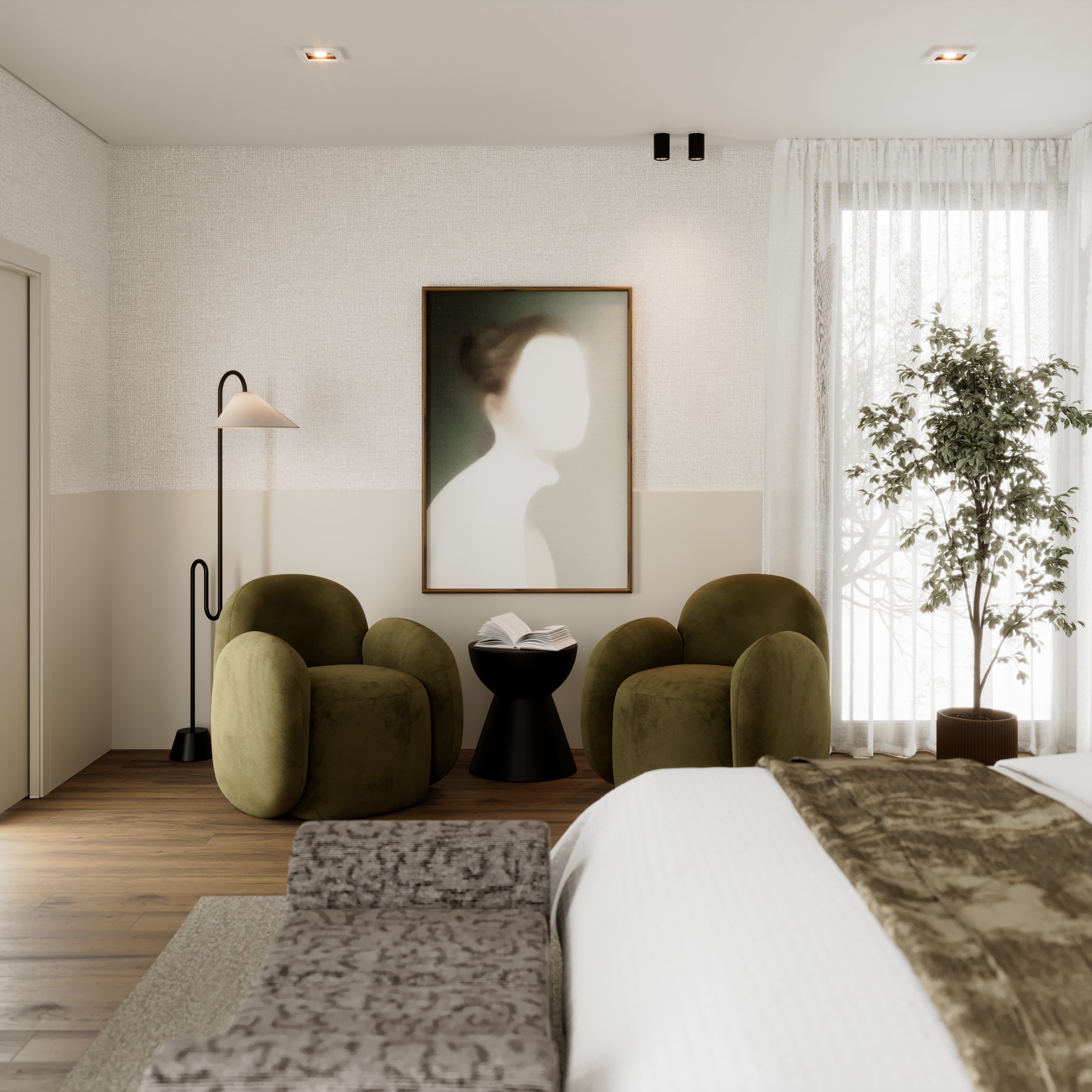 A cozy hotel room living area with two green velvet armchairs, a small black side table holding an open book, a tall floor lamp, a large framed portrait on the wall, a potted plant by a window with sheer curtains, and part of a bed with a patterned throw blanket.