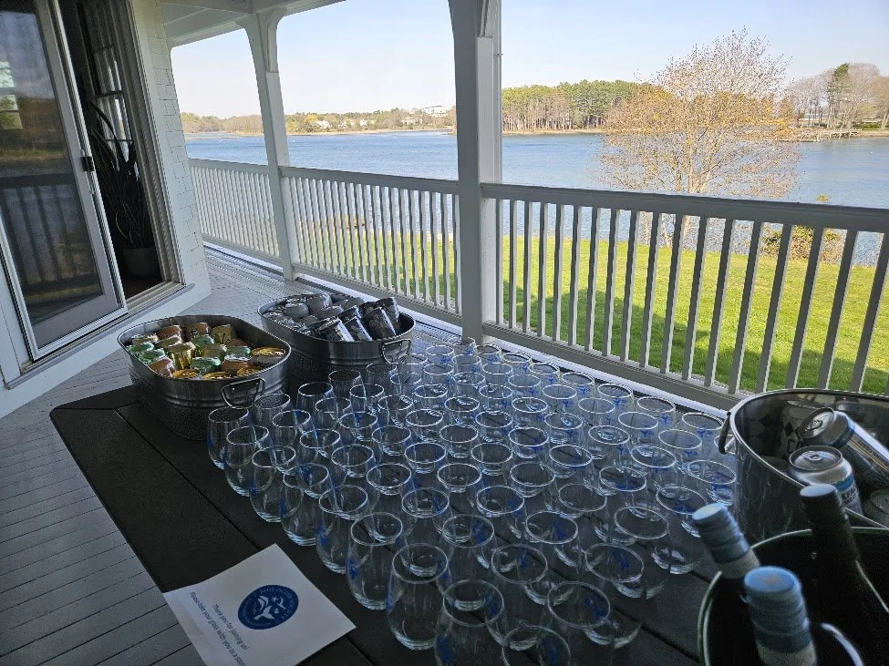 Glasses and beverages on a table with water in the background