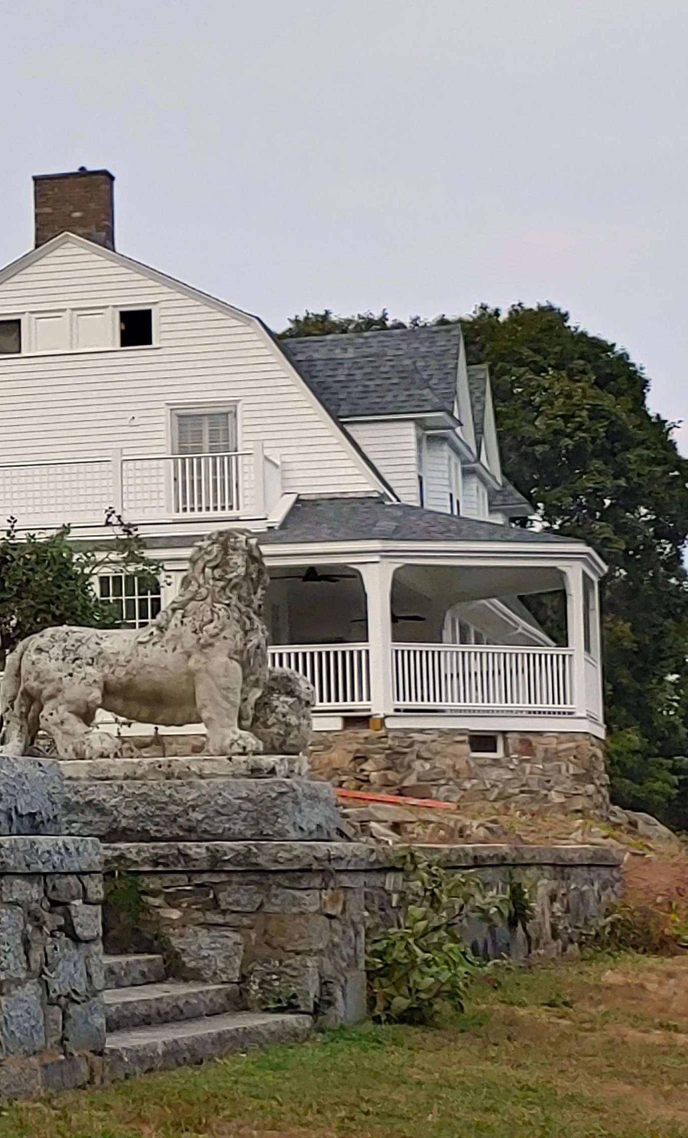 Stone lion in front of a white house on a hill