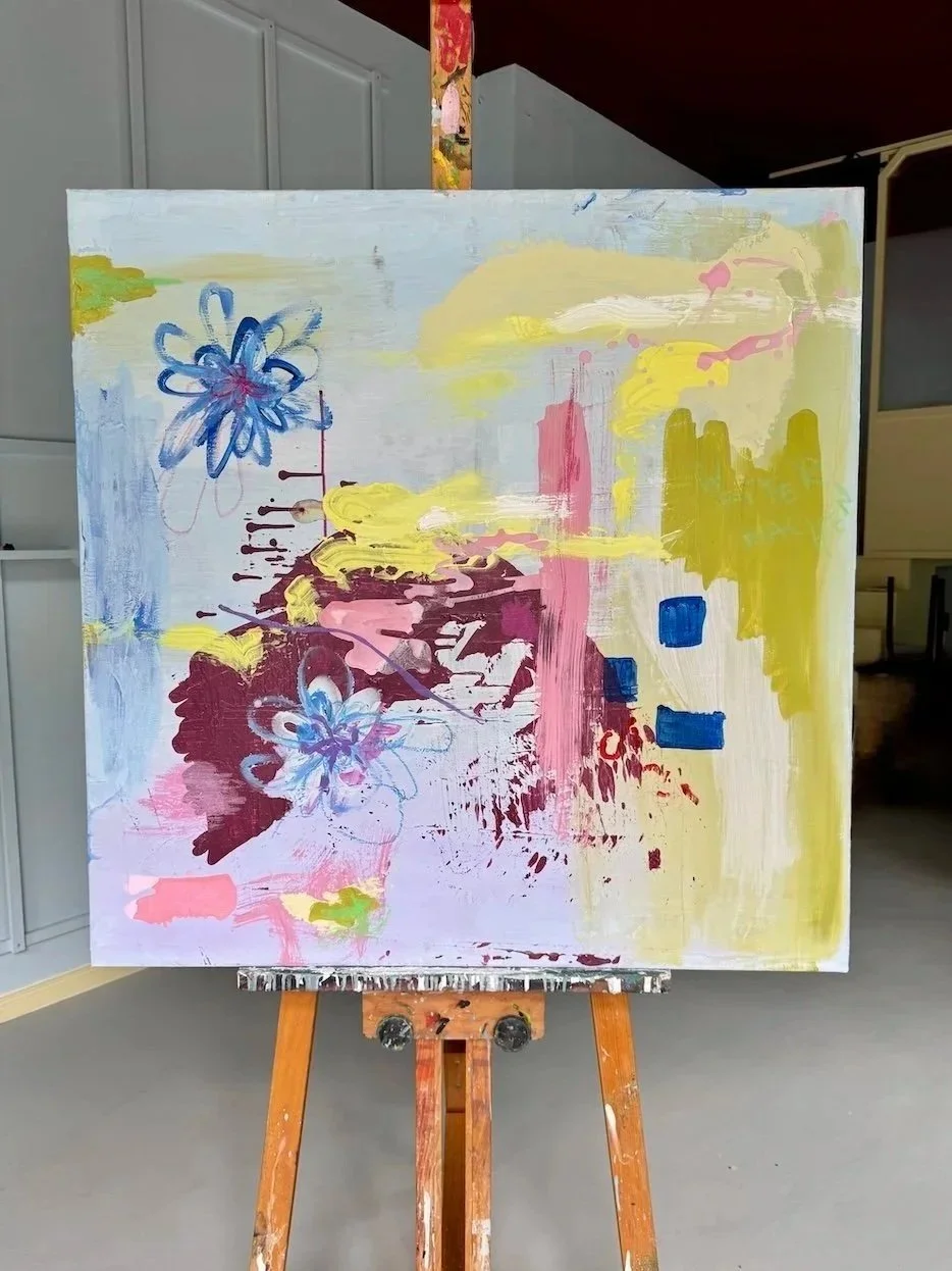 Ein abstraktes Gemälde mit Pastellfarben, blauen, rosa, gelben und grünen Akzenten, auf Leinwand aufgestellt auf einem Staffelei.