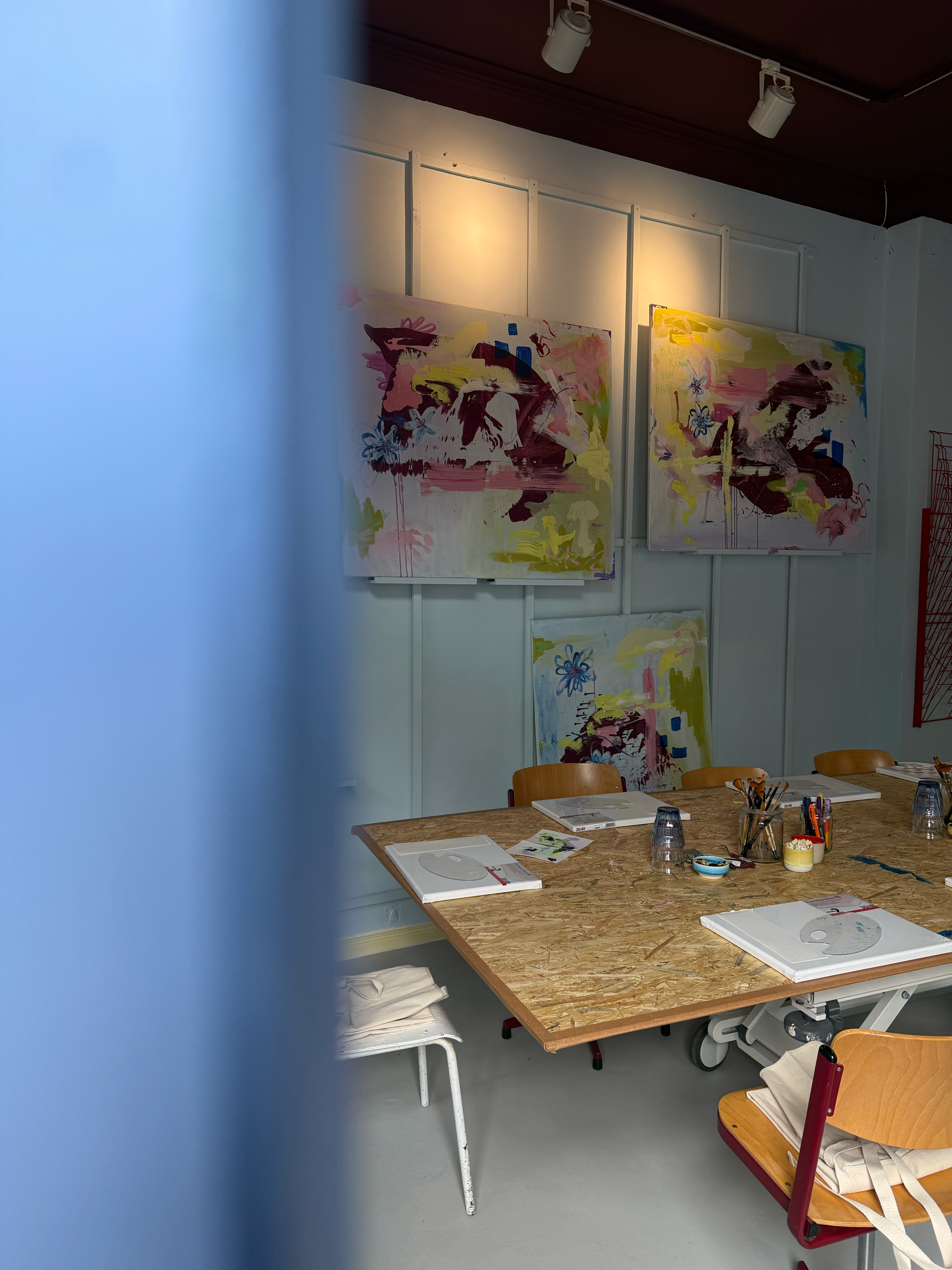 Ein Tagungsraum mit einem großen Tisch, auf dem Papier, Stifte und Glaswaren stehen. Im Hintergrund hängen mehrere abstrakte Gemälde an der Wand.