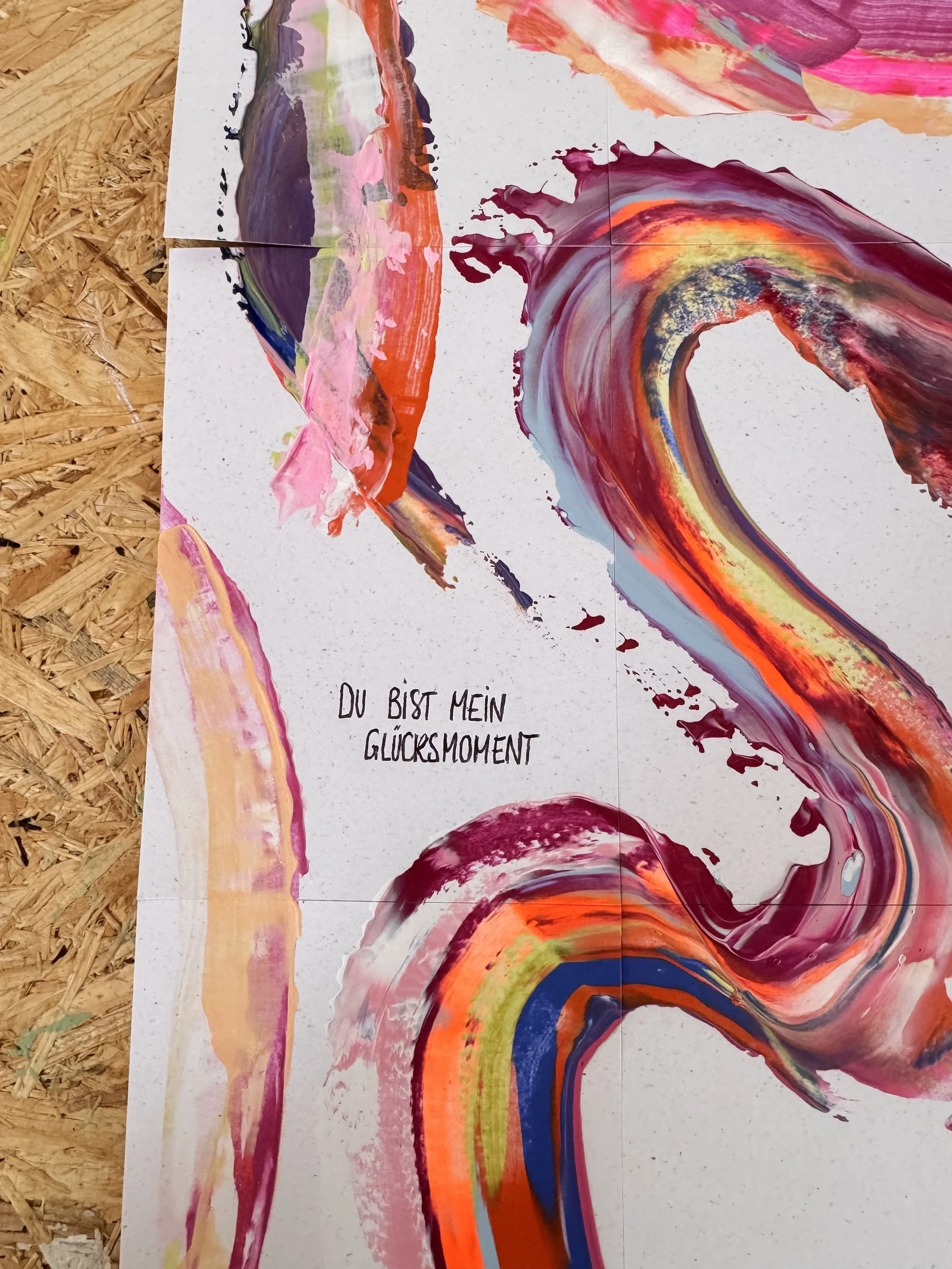 Bunte Acrylmalerei in abstrakter Form mit wirbelnden Linien und Farbschichten, darunter ein Text in Deutsch: 'Du bist mein Glücksmoment'.