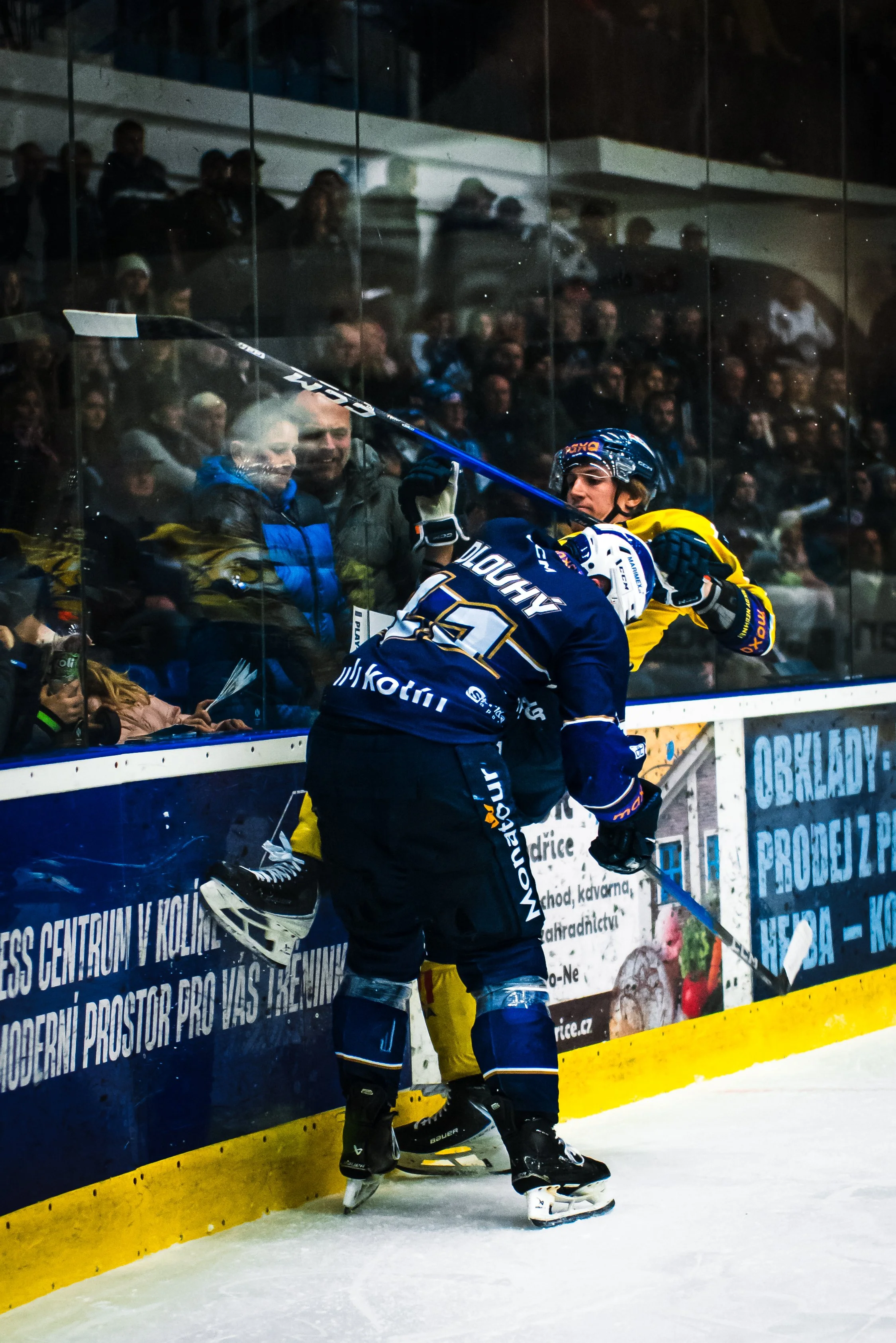 Hockey players fighting near the rink's glass barrier during a game.