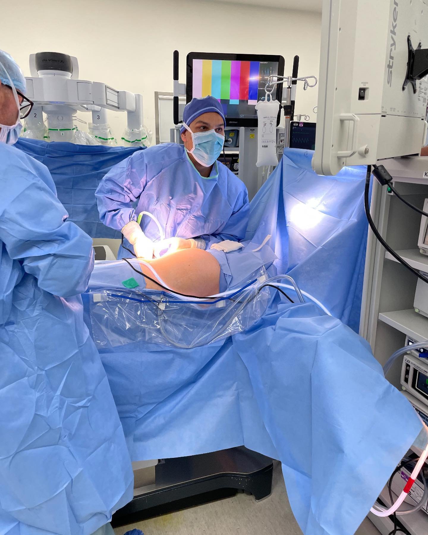 Medical team performing a surgery in operating room with medical equipment and monitors.