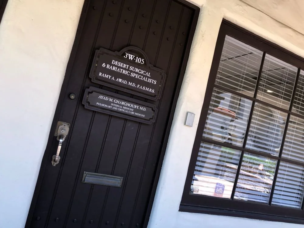 Black door with signs for Desert Surgical & Bariatric Specialists, and Dr. Ramy A. Awad, located beside a window with horizontal blinds.