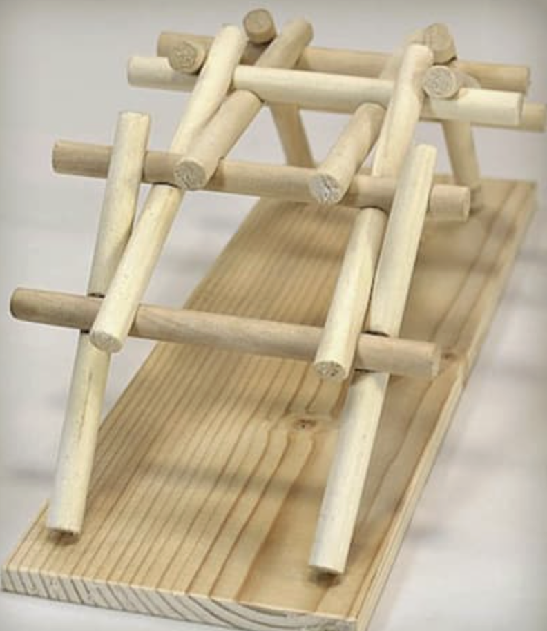 A miniature wooden boat with a flat base and a simple frame structure made of light-colored small wooden logs and planks.