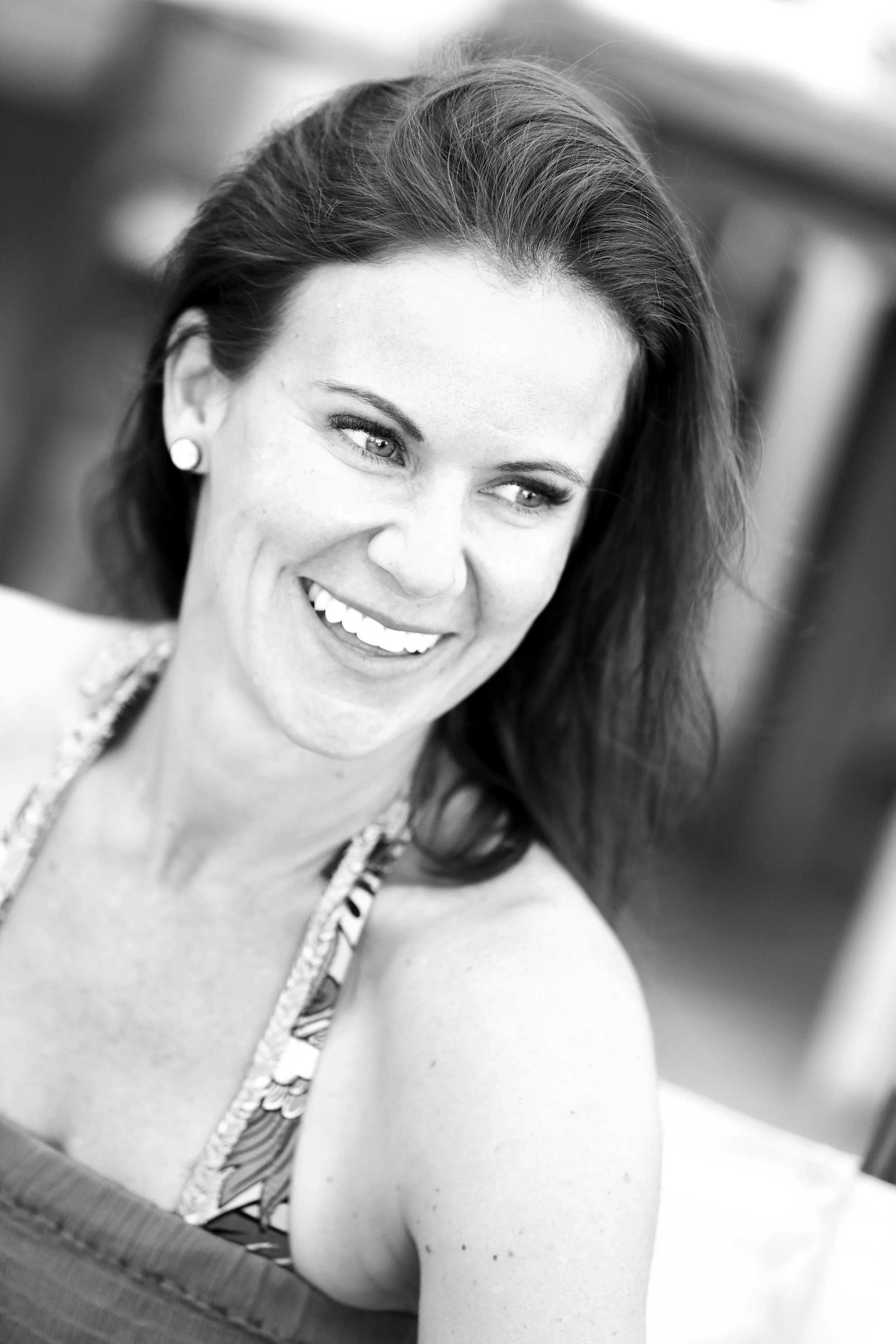 Black and white photo of the founder of Purposeful Wanderings, a smiling woman with dark hair, wearing earrings and a patterned top.