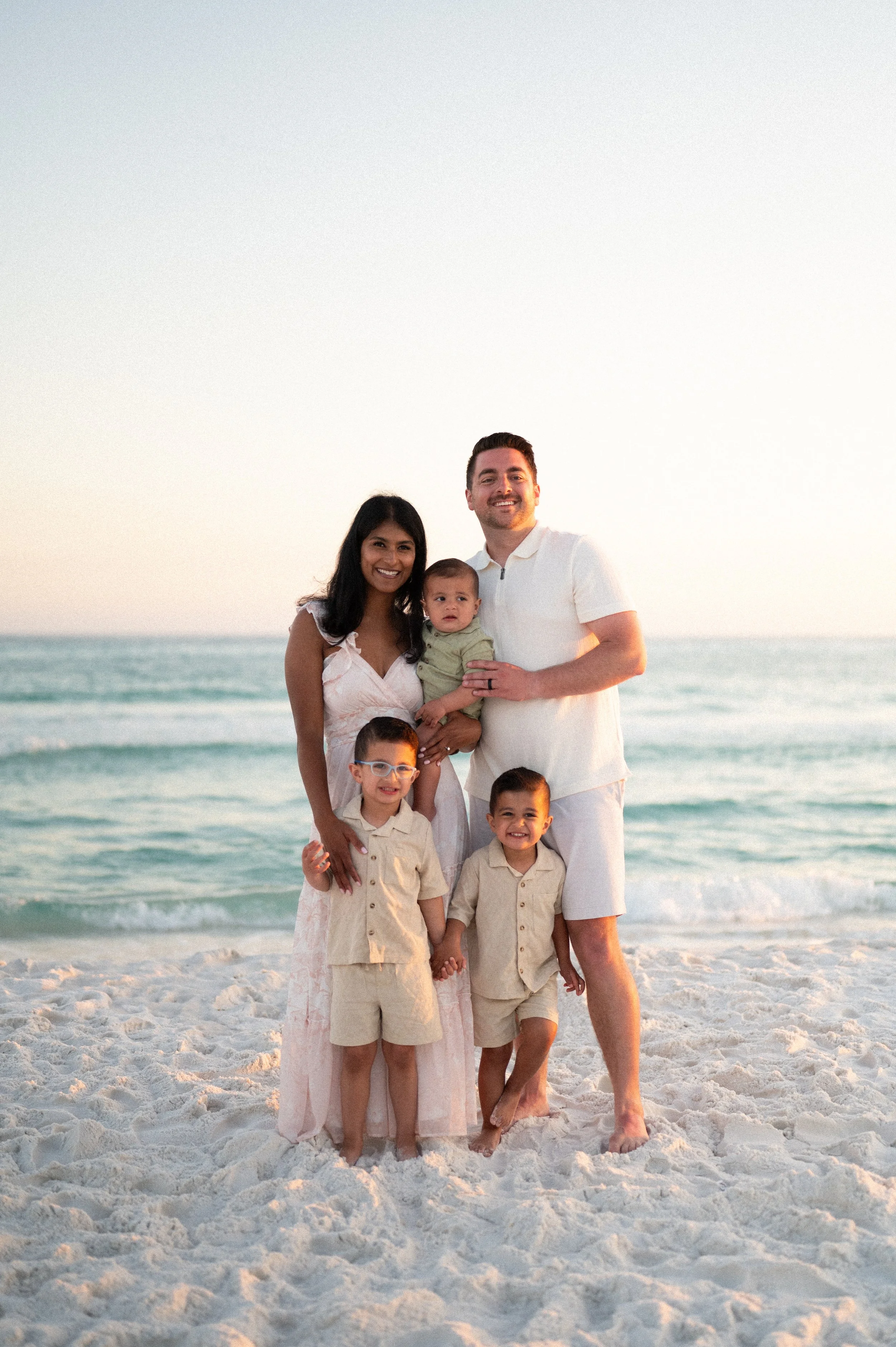 Two floral arrangements with peach, pink, purple, and white flowers on a white tablecloth, with a patterned wallpaper featuring detailed pastoral scenes and buildings in the background.