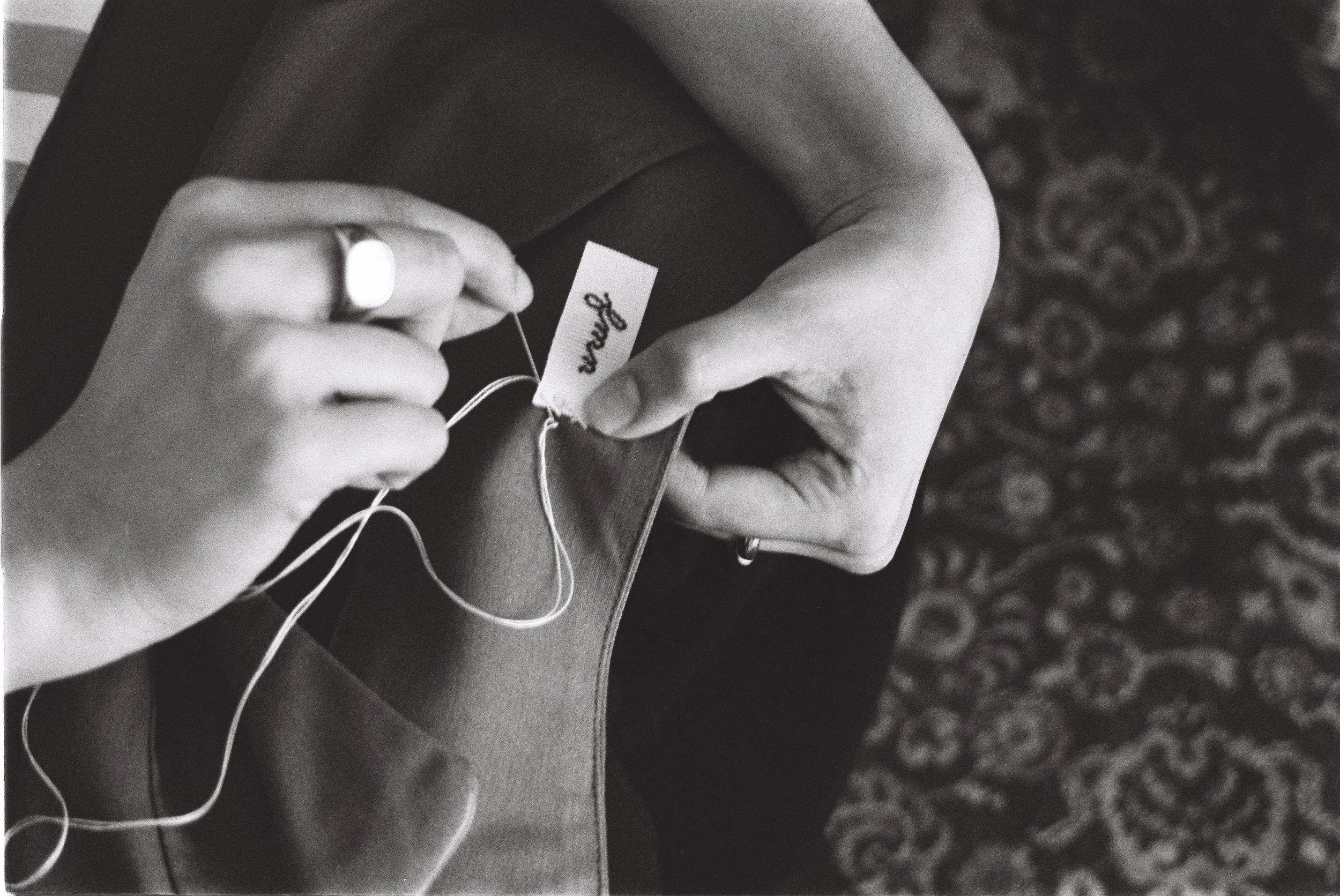 every detail is being taken care of - cosiendo con costura herringbone la etiqueta de la marca a la prenda