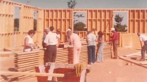 People working on a construction site assembling wooden framing for a building.