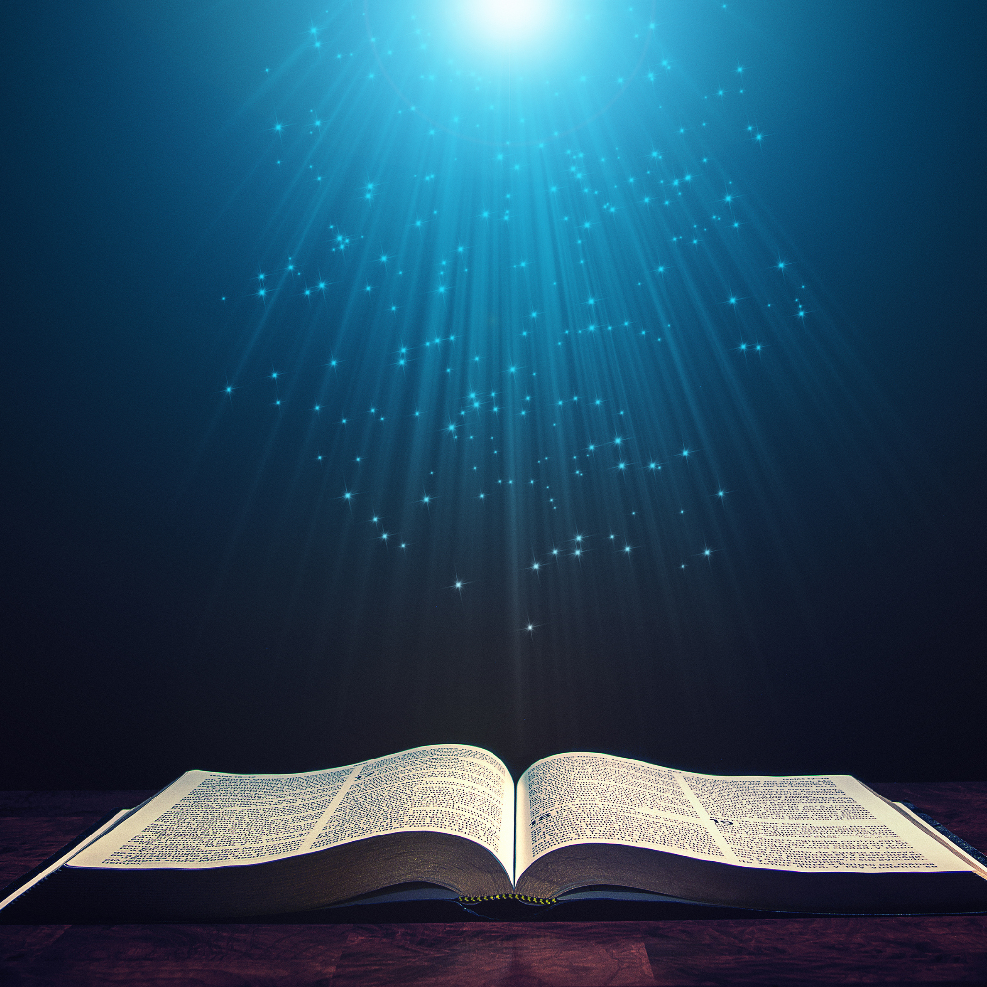 An open book with glowing light and sparkles shining down from above, creating a mystical and magical atmosphere.