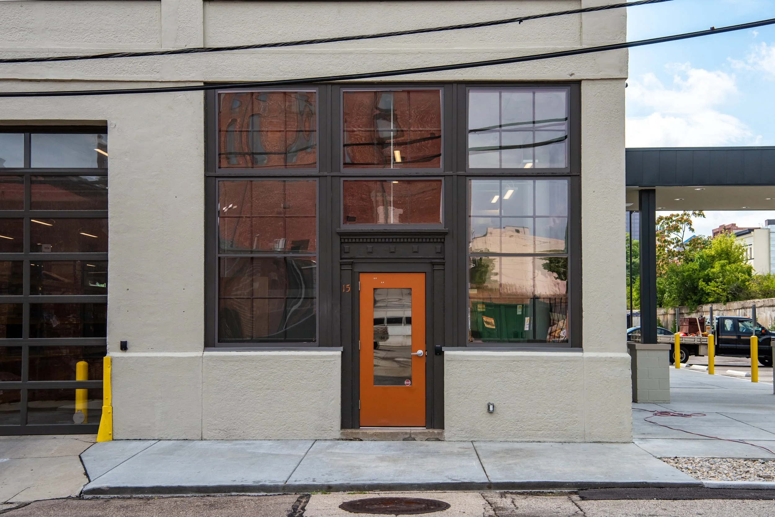 The Dayton Motor Car Building exterior in daylight, a five-story historic concrete industrial building with rows of original multi-pane windows, located on a corner lot in the Oregon East District of downtown Dayton, Ohio.