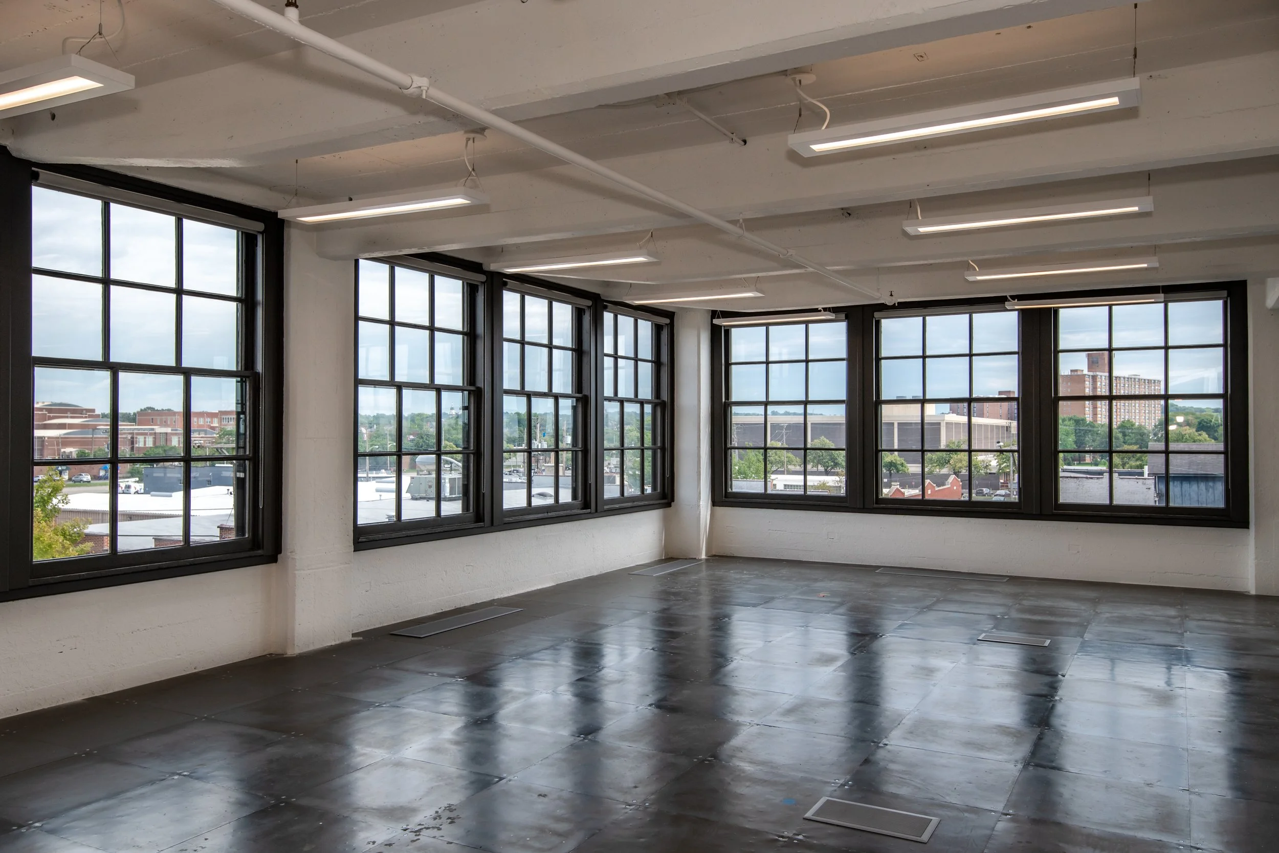 Open office floor plate at the Dayton Motor Car Building featuring polished concrete floors, abundant natural light from oversized original multi-pane windows, and flexible open layout space in downtown Dayton, Ohio.