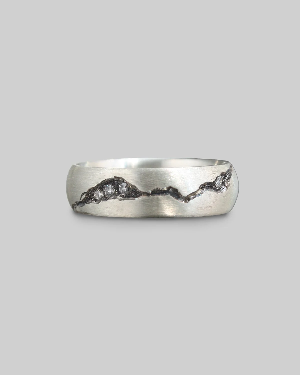 Anello in argento con frattura incisa a mano e diamanti incastonato all'interno.