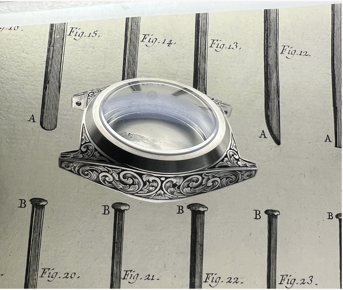 Un a cassa di orologio U2 Classic di UNIMATIC  in inox con incisioni decorative stile scrollwork, posizionato sopra un illustrazione vintage raffigurante dei chiodi.