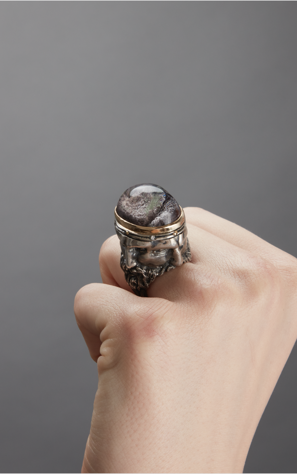 Anello statement scultoreo con volti scolpiti e grosso quarzo incastonato.