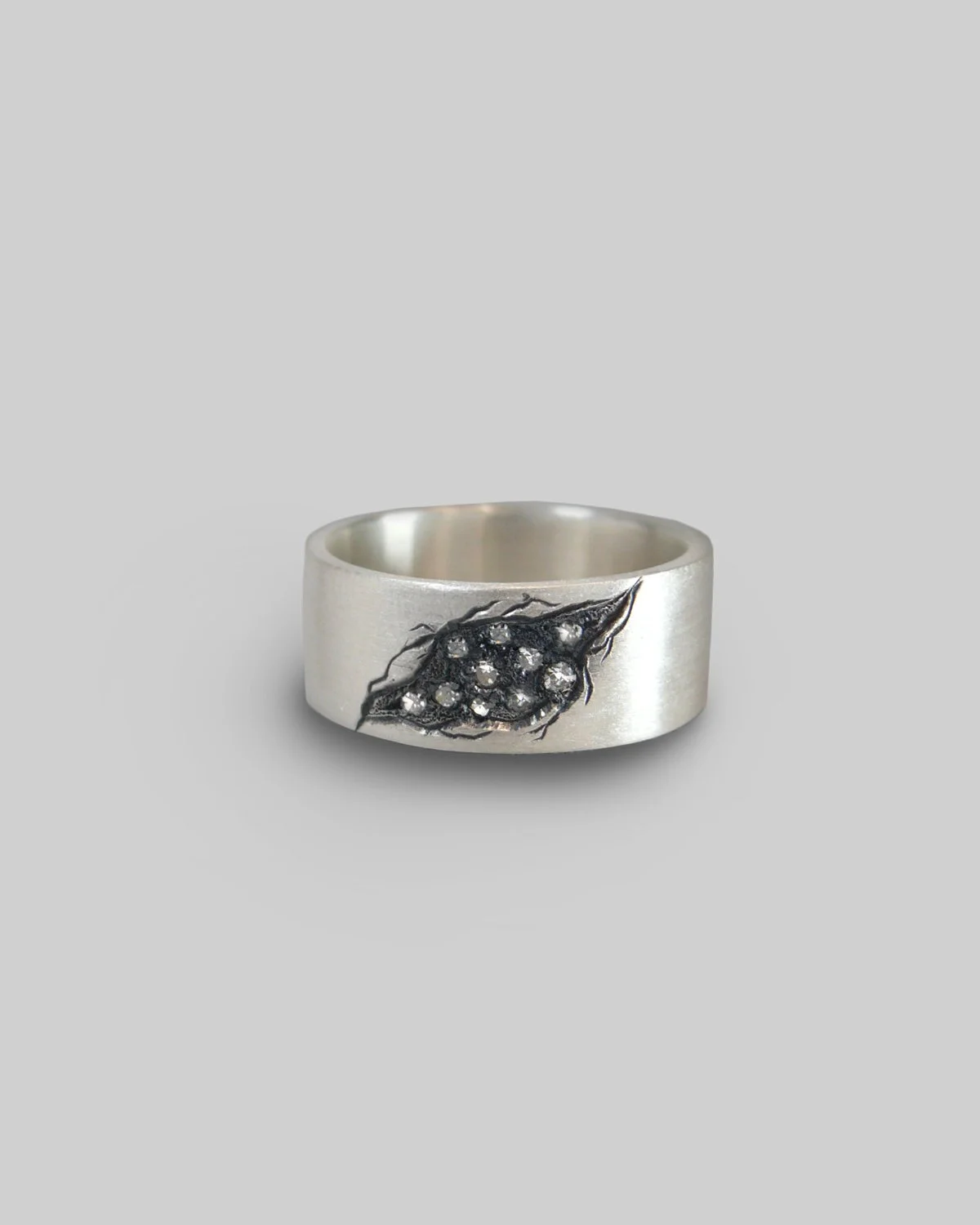 Anello a fascia in argento con grossa erosione incisa e brunita a contrasto con argento satinato e diamanti incastonati al suo interno.