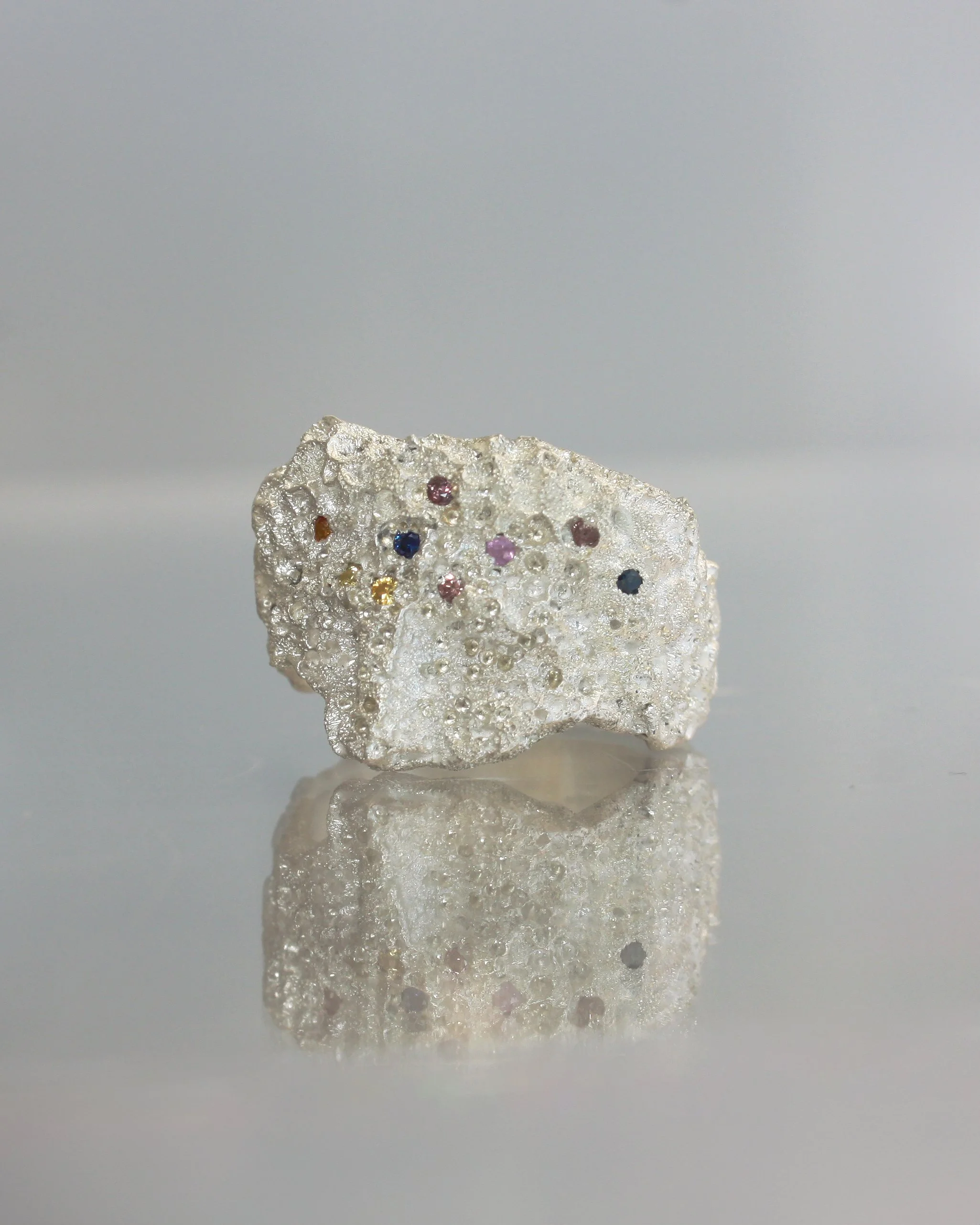 Anello IDOL nebula in argento, lavorazione porosa allover e incastonatura zaffiri colorati.