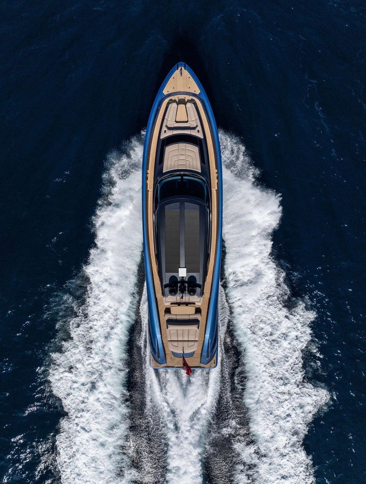 Aerial view of a luxury yacht speeding through the water, creating a white wake behind it.