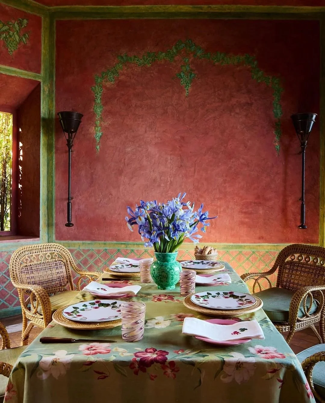 Moroccan-inspired dining room in Tangier with deep terracotta walls, woven seating and colourful Mediterranean table styling.
