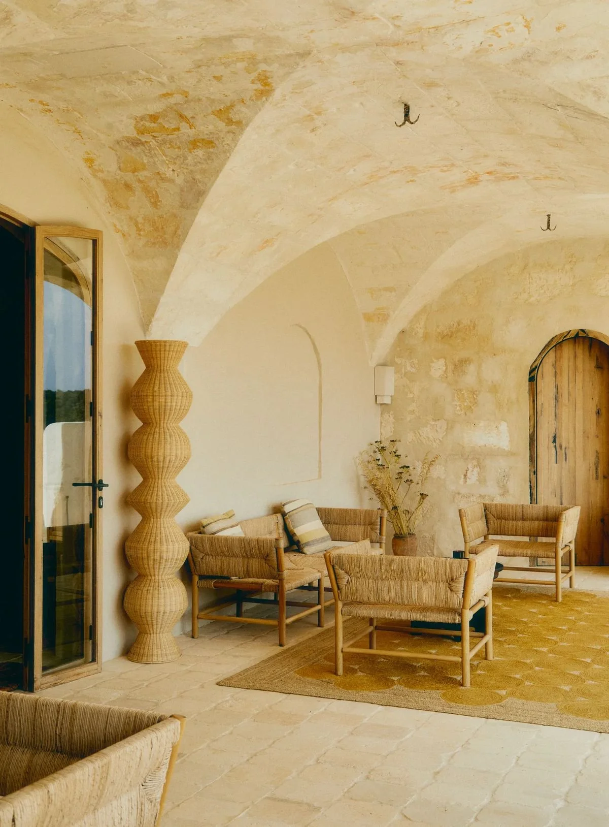 Rustic Mediterranean interior with natural materials, textured walls and woven furniture.