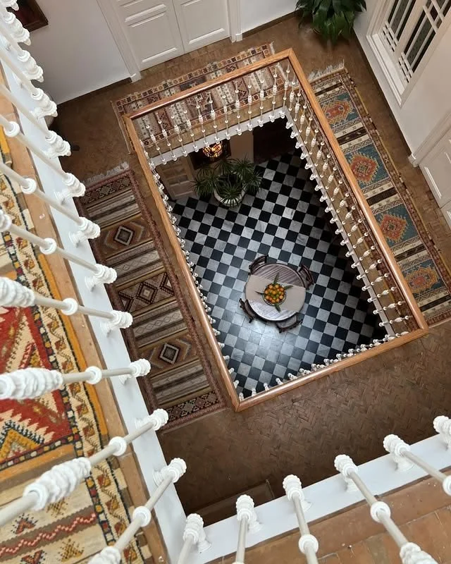 Traditional Moroccan riad interior in Tangier featuring checkerboard flooring, layered textiles and architectural symmetry.
