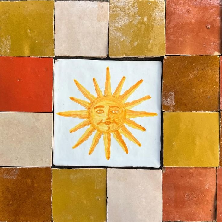 Hand-painted Mediterranean ceramic tile with sun motif in warm earthy tones and artisanal texture.