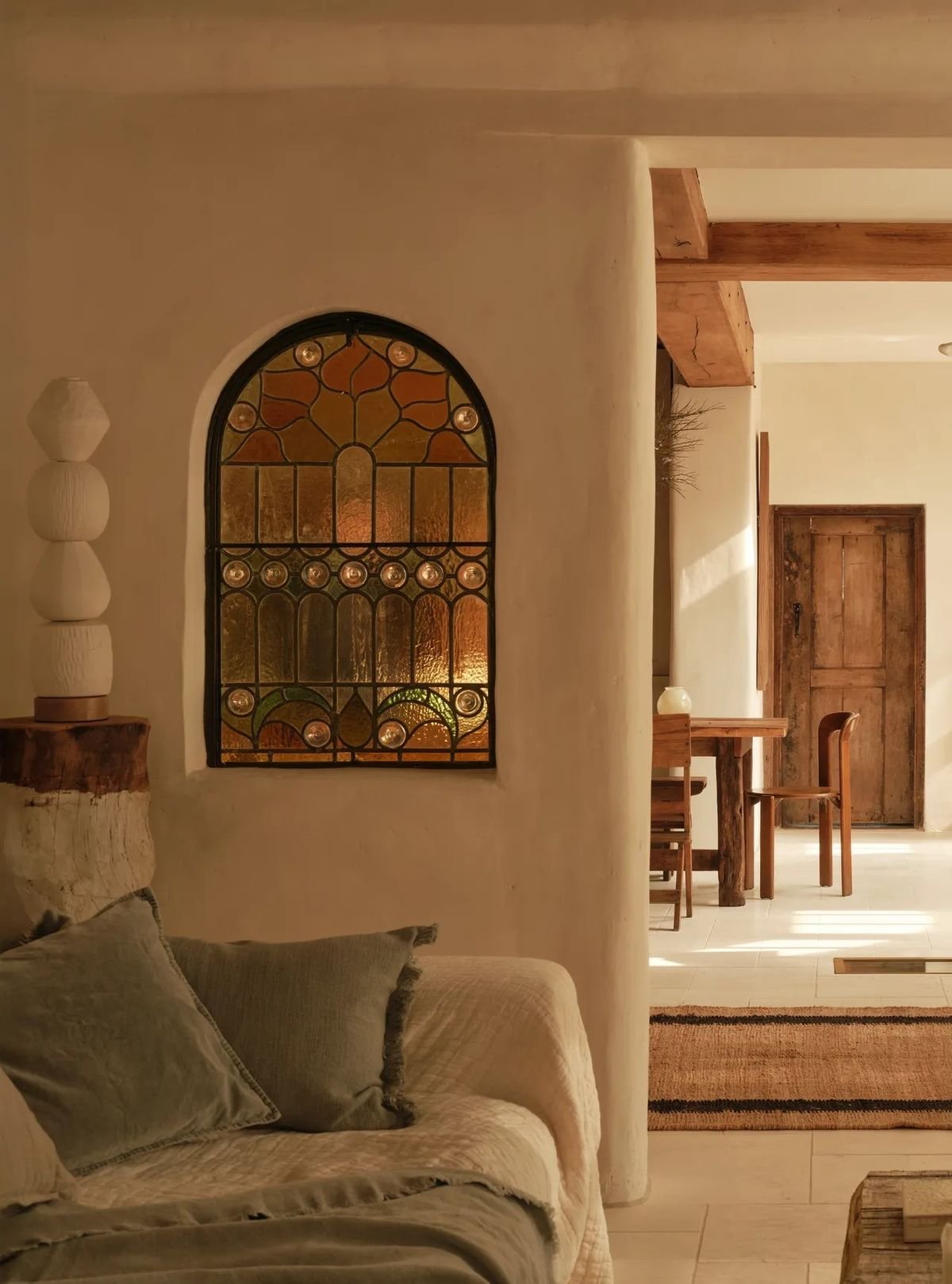 Mediterranean-inspired interior with textured plaster walls, stained glass window details and warm earthy tones.