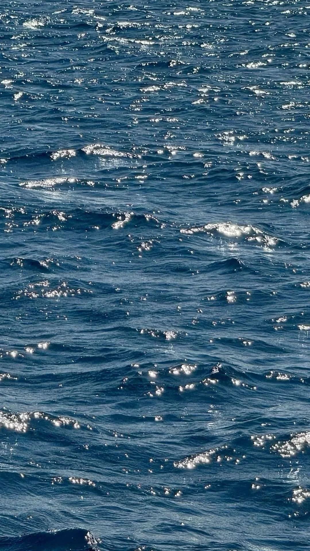 Sunlight reflecting on Mediterranean sea water with deep blue natural textures.