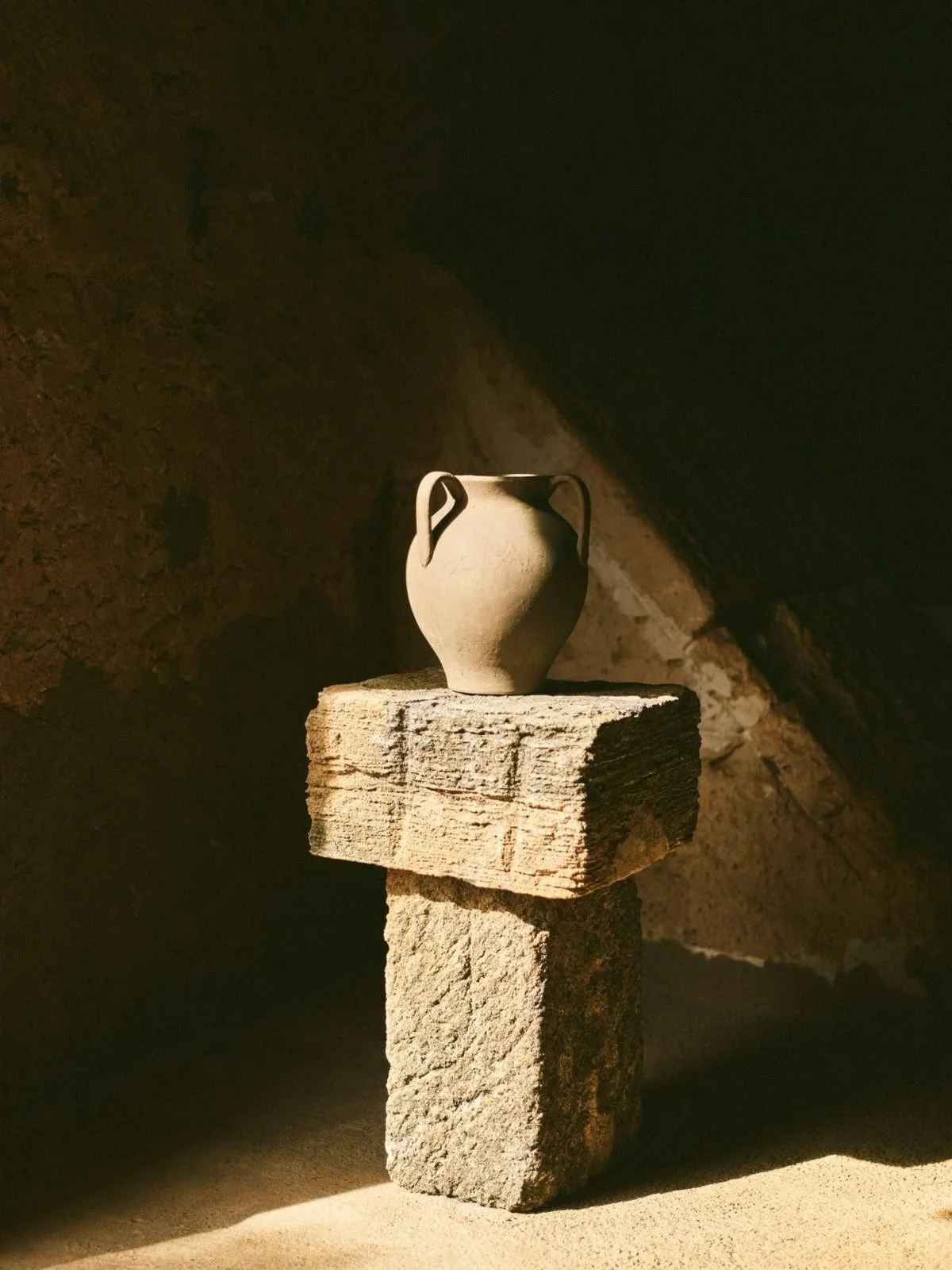Atmospheric still life with sculptural ceramic vessel and warm shadow play in an editorial interior styling setting.