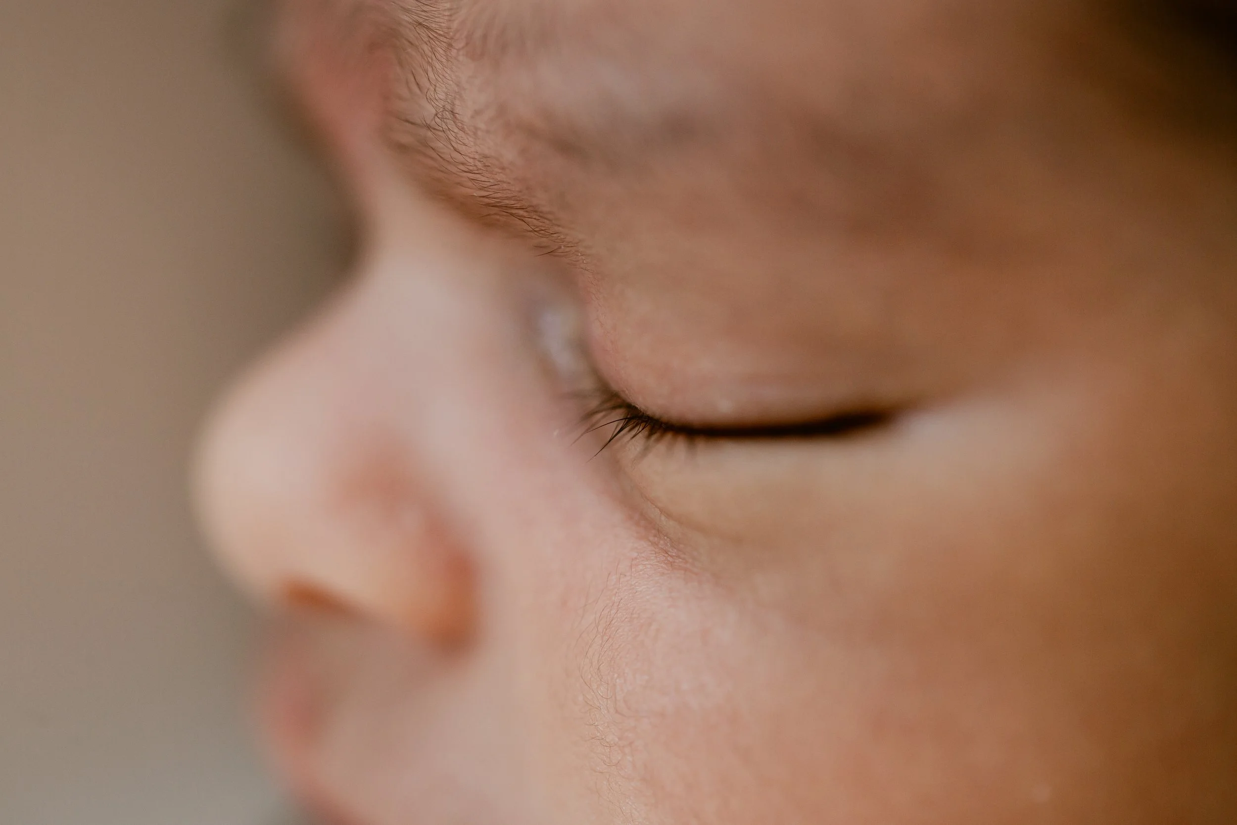 Close-up of a baby's face, focusing on the closed eye and eyebrow.