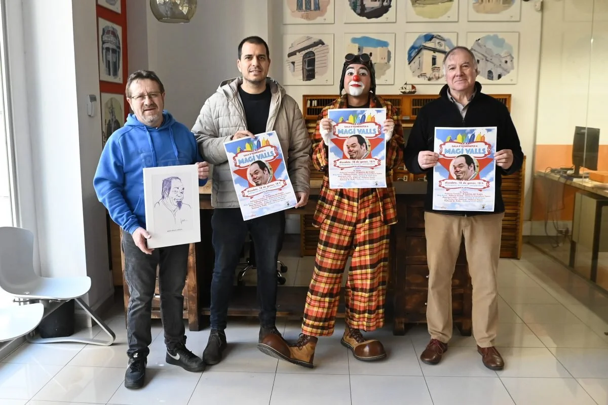 Cuatro hombres y una payaso con maquillaje y traje de cuadrados rojos, amarillos y negros, sosteniendo carteles en un interior con paredes decoradas con cuadros de casas y una sección de techo de lámpara colgante.