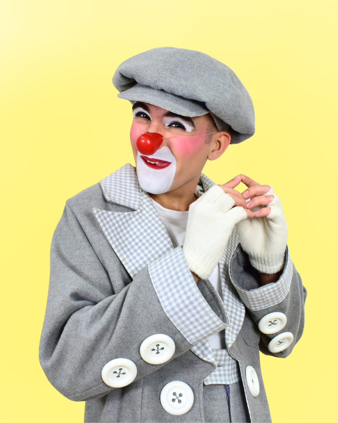 Payaso con peluca gris, bigotes blancos y nariz roja de payaso, vestido con abrigo gris con botones grandes blancos, guantes blancos, y fondo amarillo.