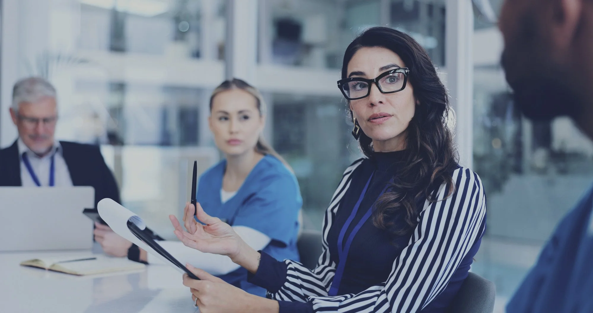 A diverse group of medical and administrative professionals collaborating around a table in a meeting.