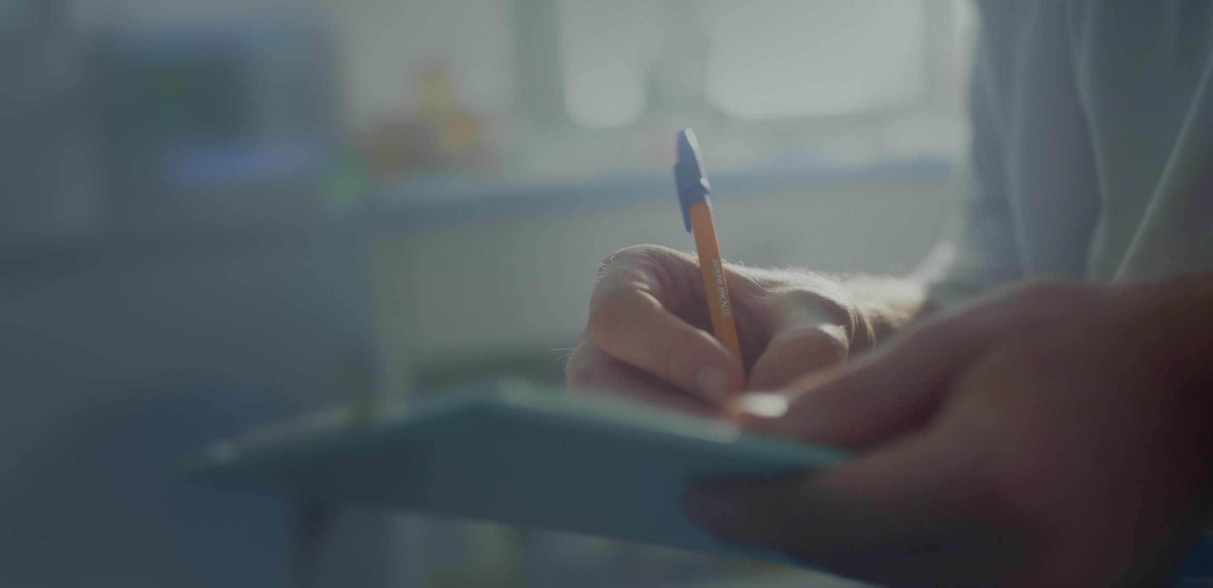 Close-up of hands actively writing on a notepad with a pen.