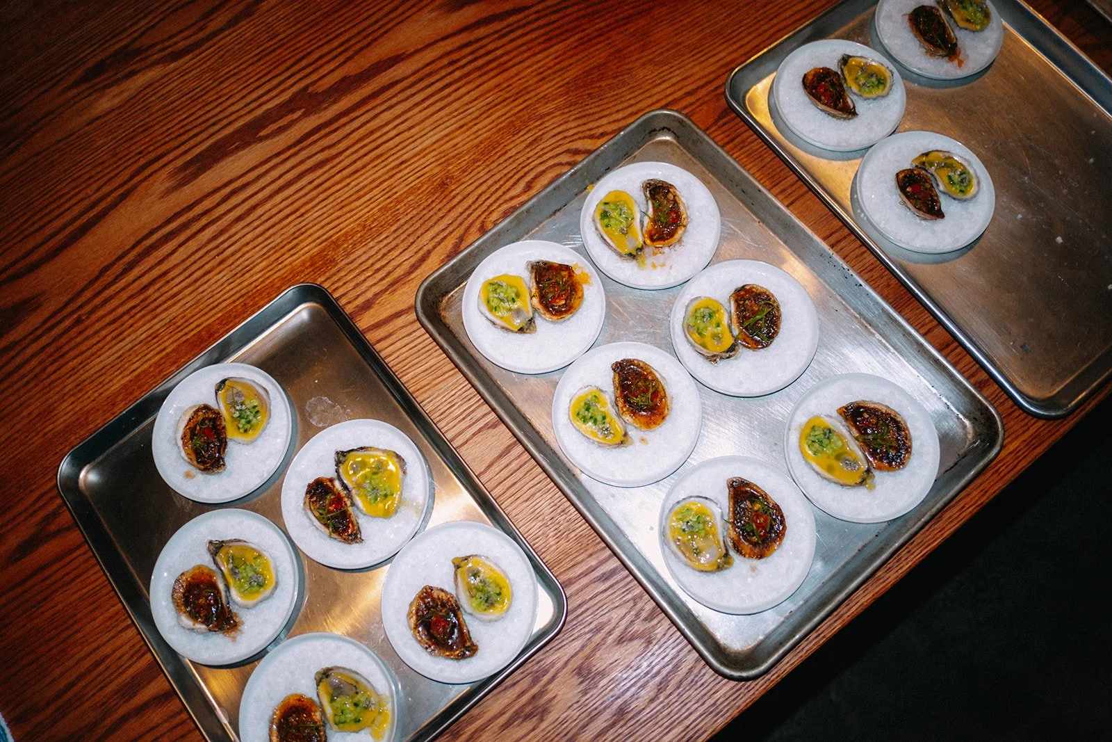 Tray of oysters with lemon and garnish on a wooden table.